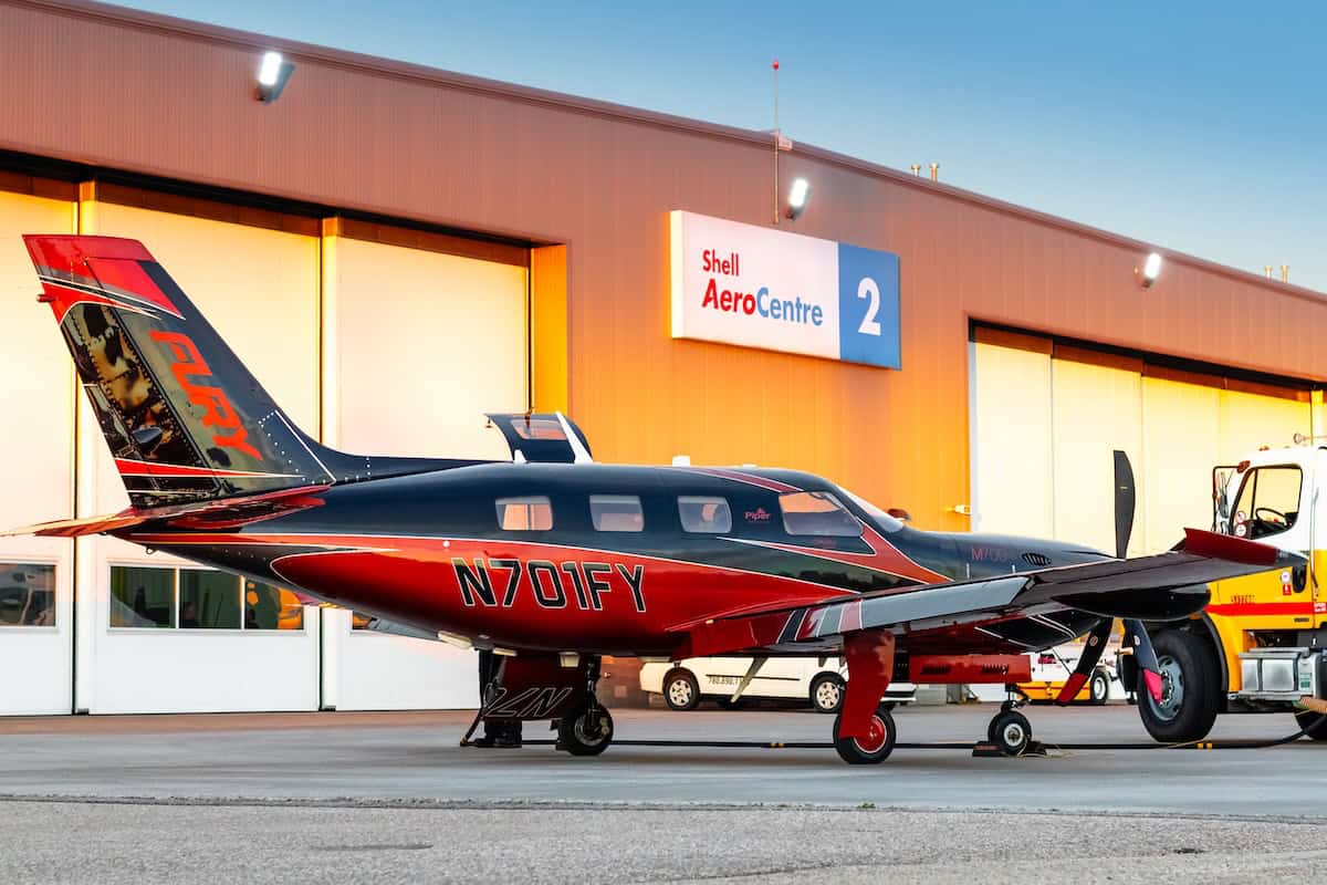 Small airplane outside hangar at sunset