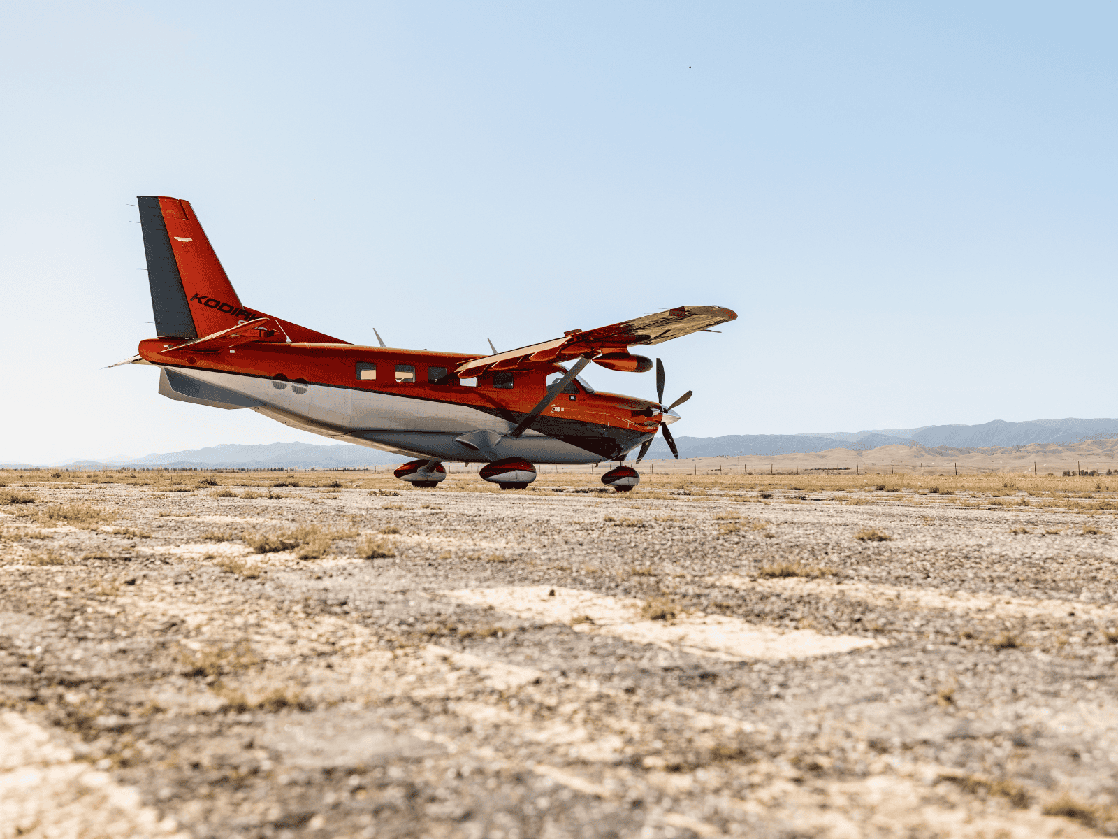 Red airplane parked on dry desert airfield