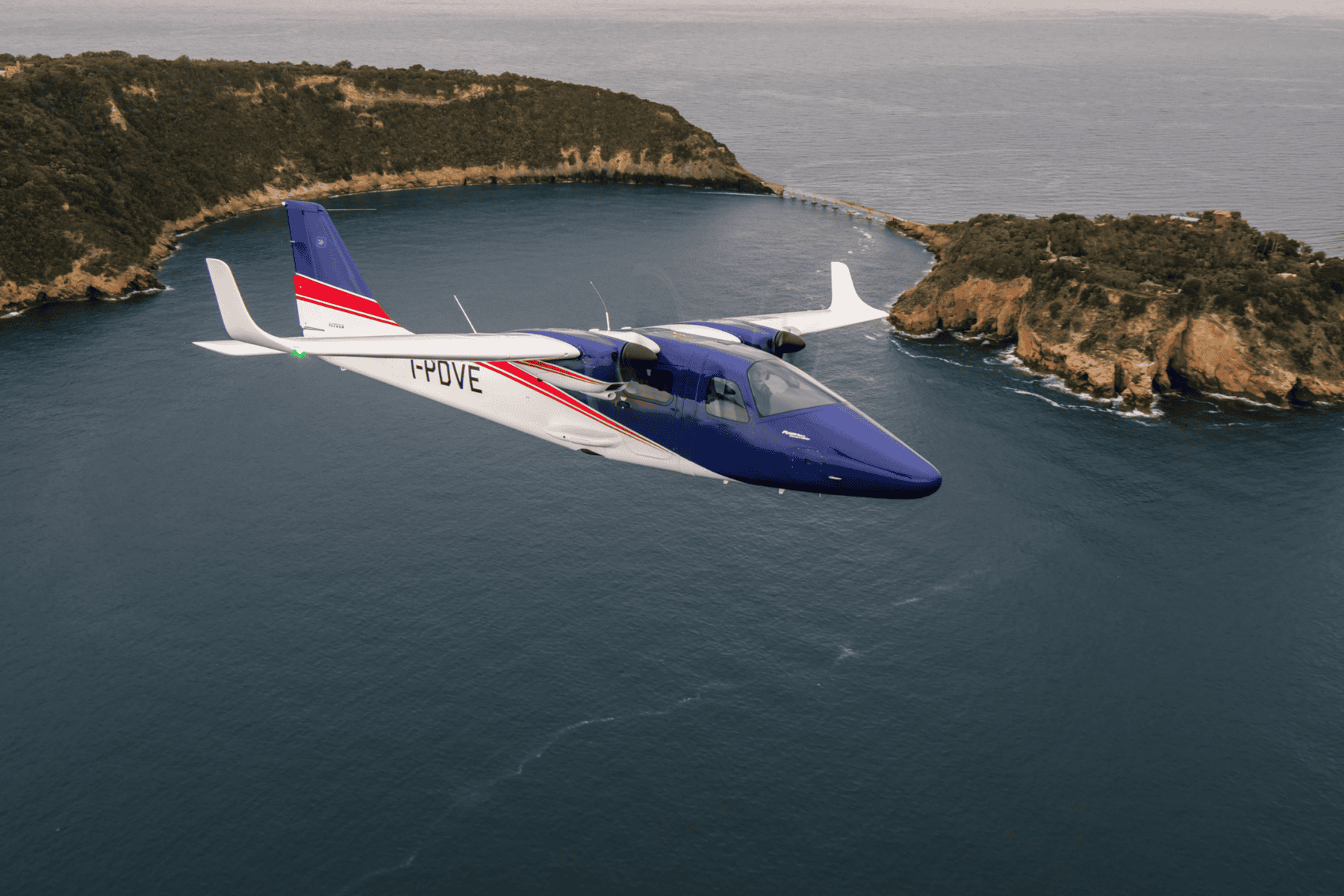 Blue aircraft flying over coastal landscape