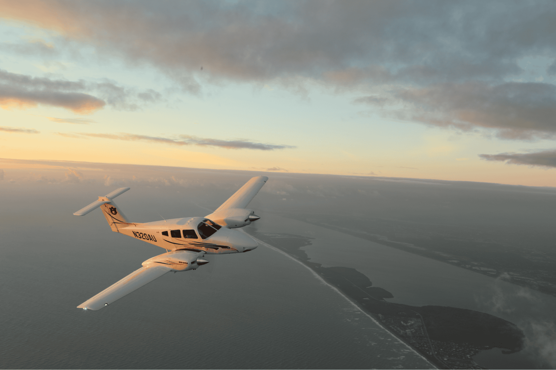Airplane flying over ocean at sunset with coastline view.
