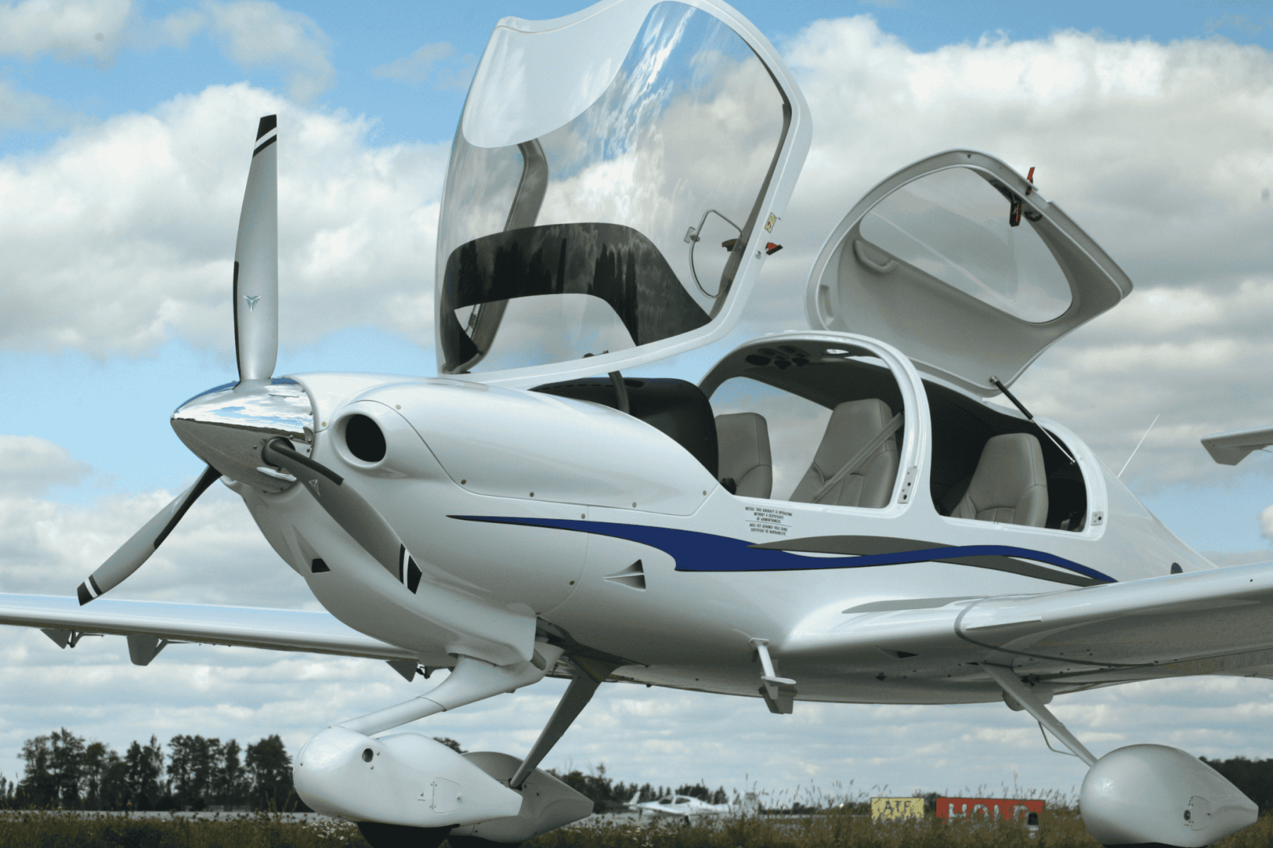 Small white airplane with open cockpit doors