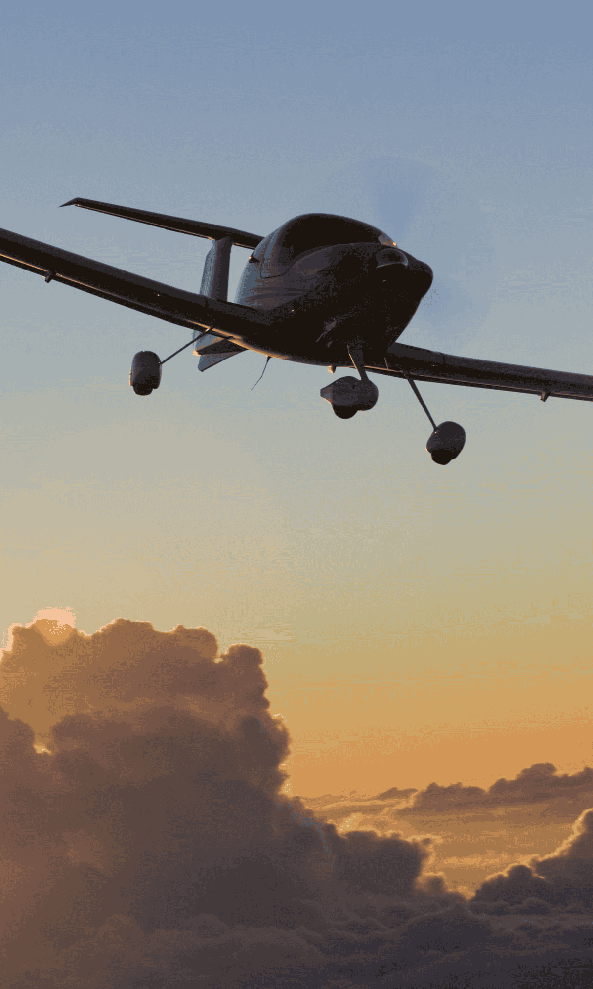 Small airplane flying at sunset with clouds