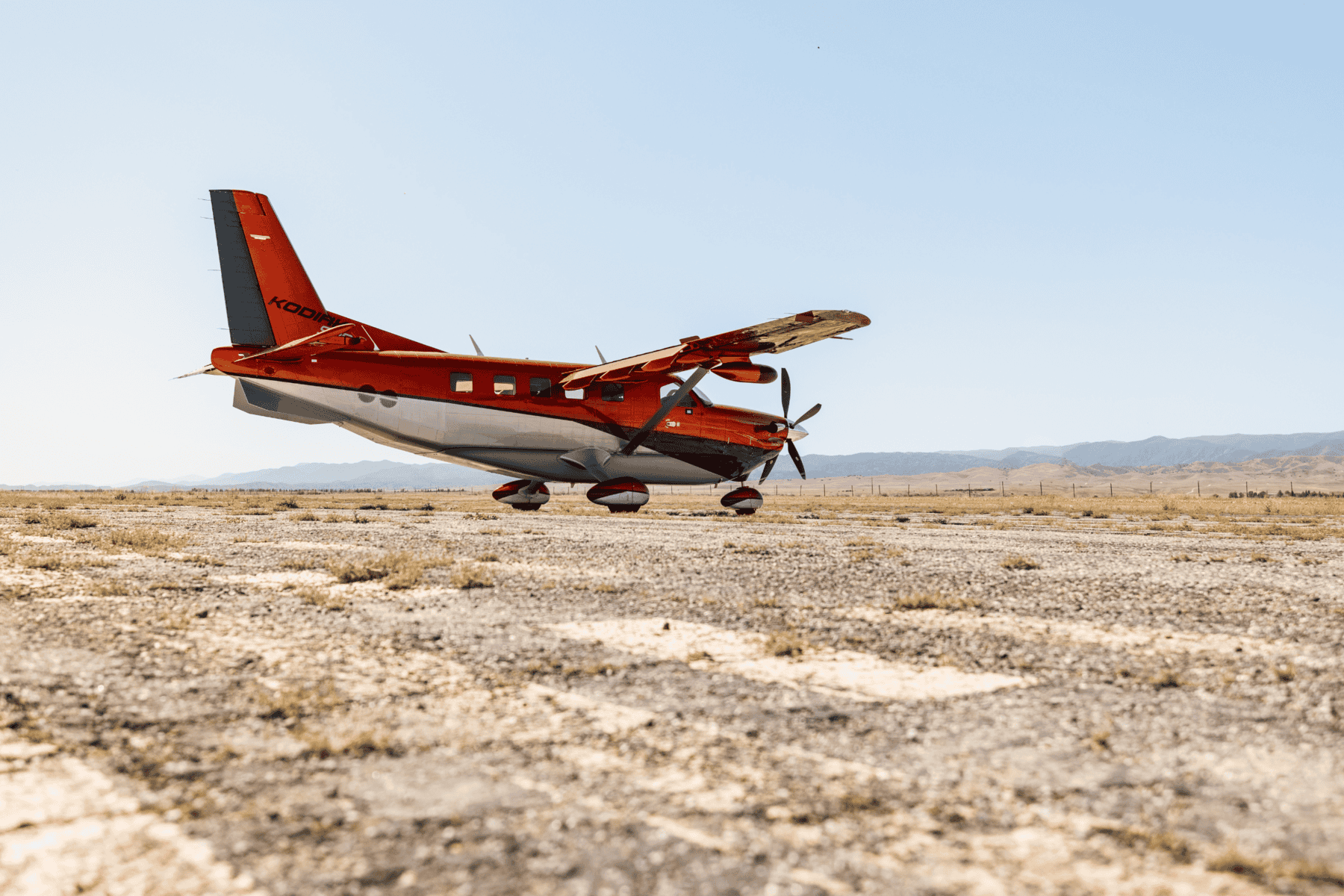 Orange aircraft parked on deserted runway