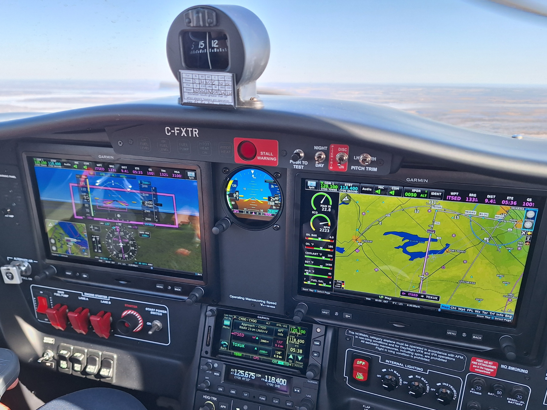 Cockpit view showing Garmin flight displays and a moving map on the right, with engine gauges and controls below in a small airplane cockpit.