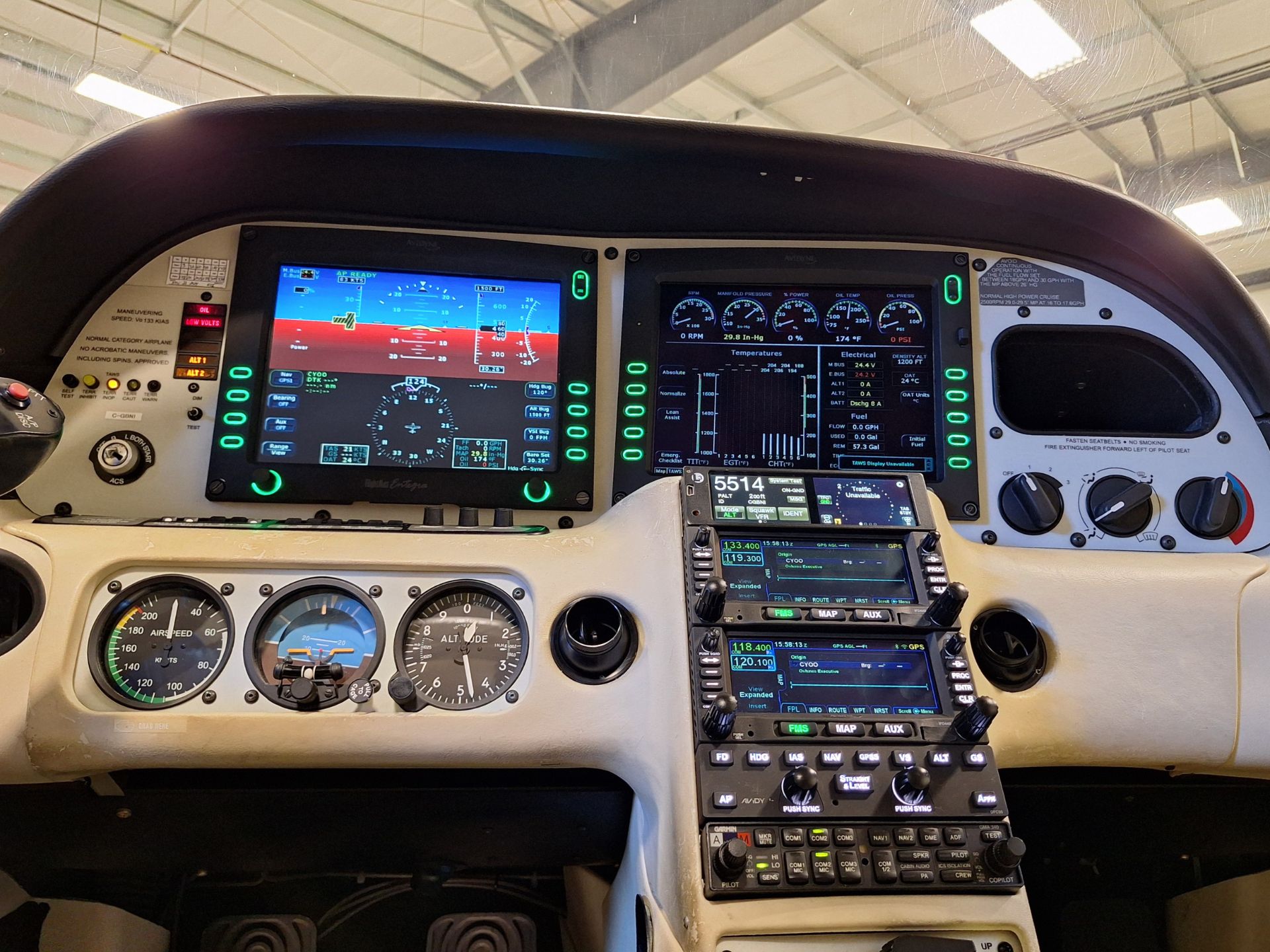 Cockpit with two large digital flight instruments, analog gauges below, and a radio stack in a light aircraft interior.