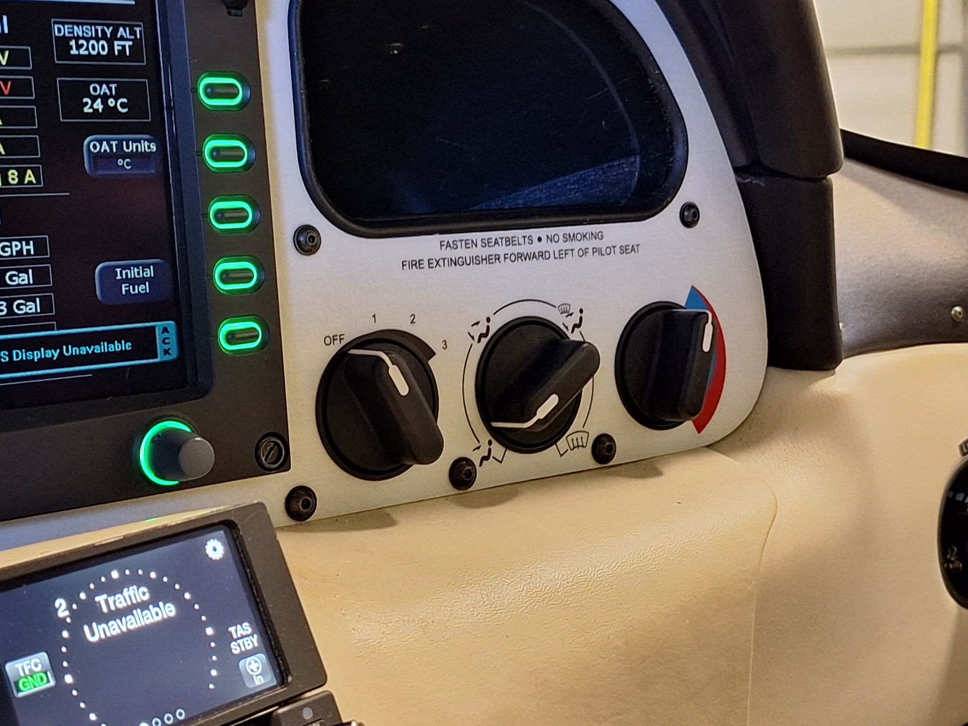 Cockpit panel with green indicator lights, digital readouts, and control knobs visible on a beige console.