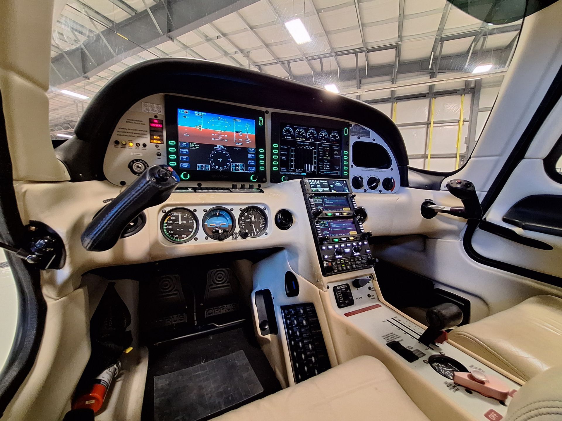 Cockpit of a small aircraft with multiple digital flight displays, instrument gauges, and center console controls visible from the pilot’s seat