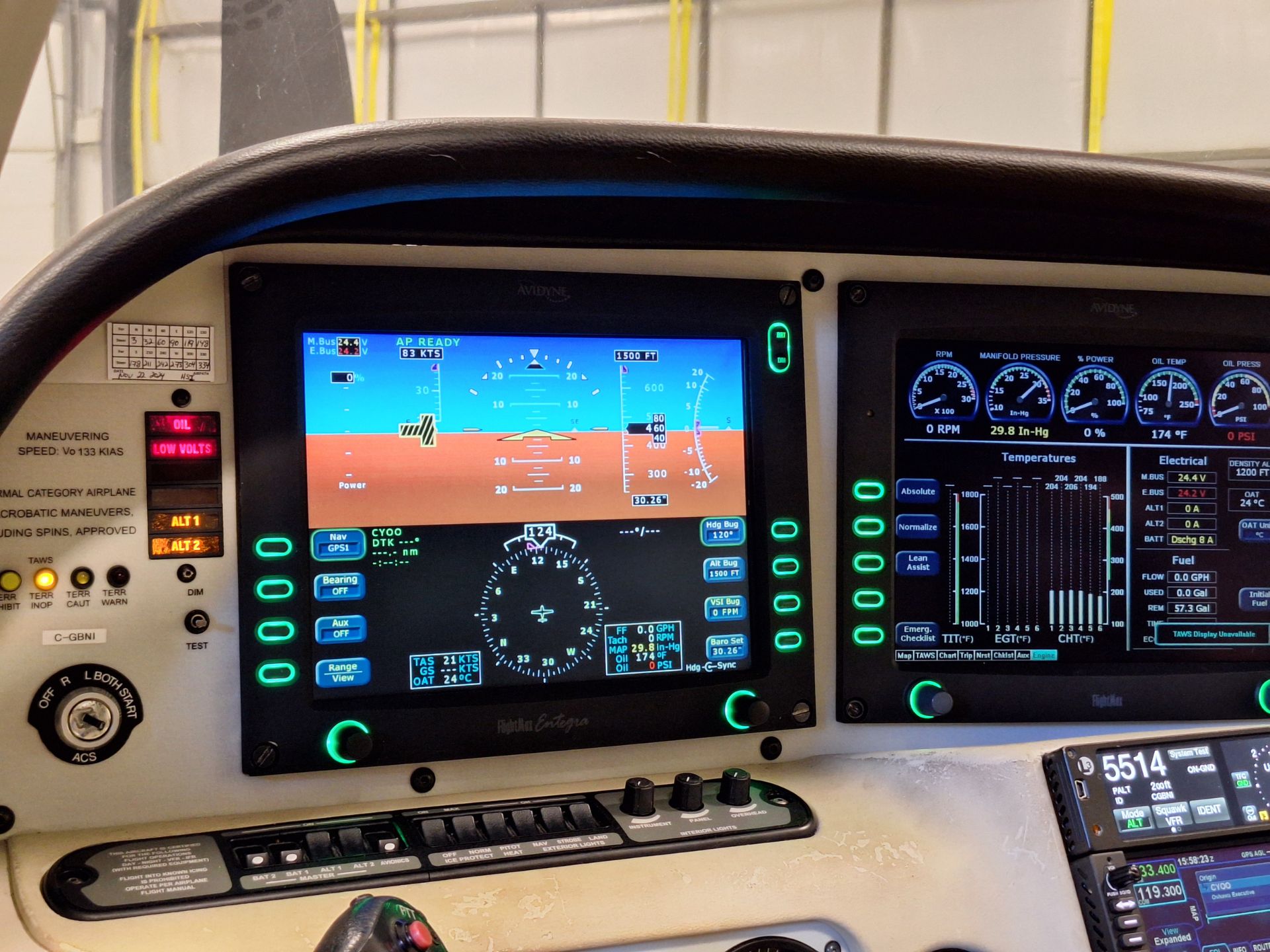 Cockpit with two large glass cockpit screens showing flight instruments and readings; green backlit controls around them.