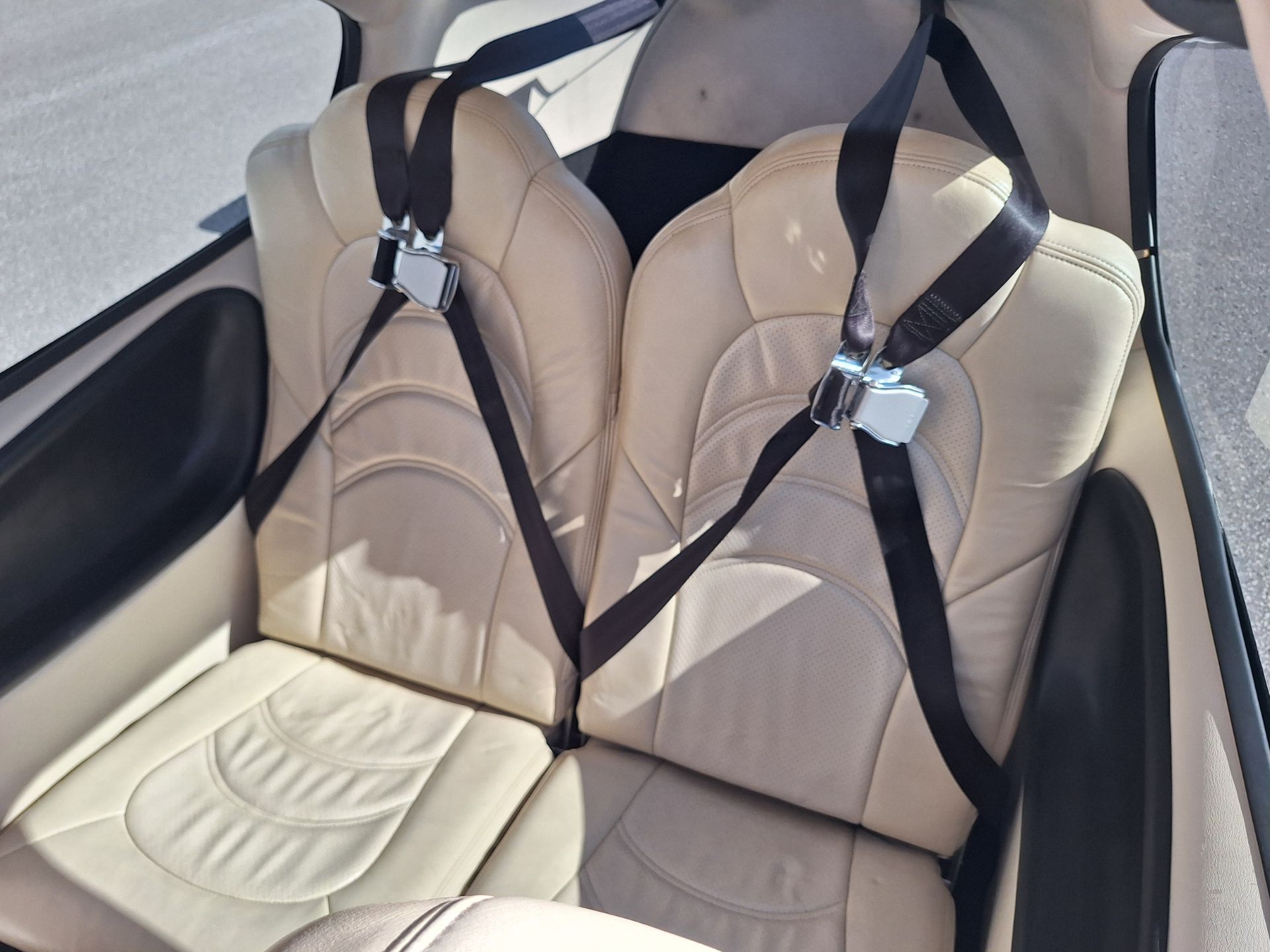 Tan leather car seats with black seatbelts and buckles visible in the back seat area.