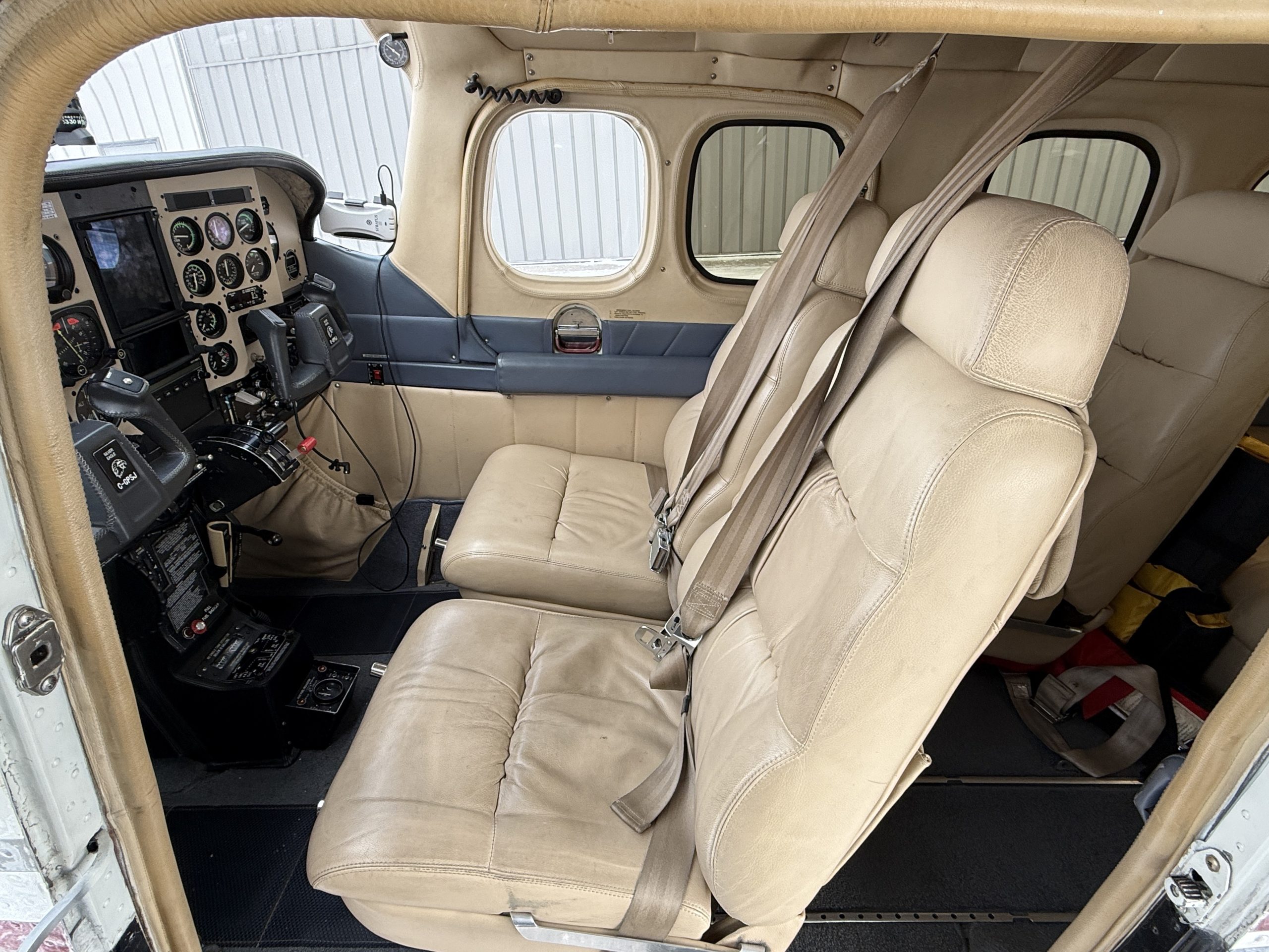 Interior of a small airplane cockpit with beige seats and instrument panel visible in the front cabin