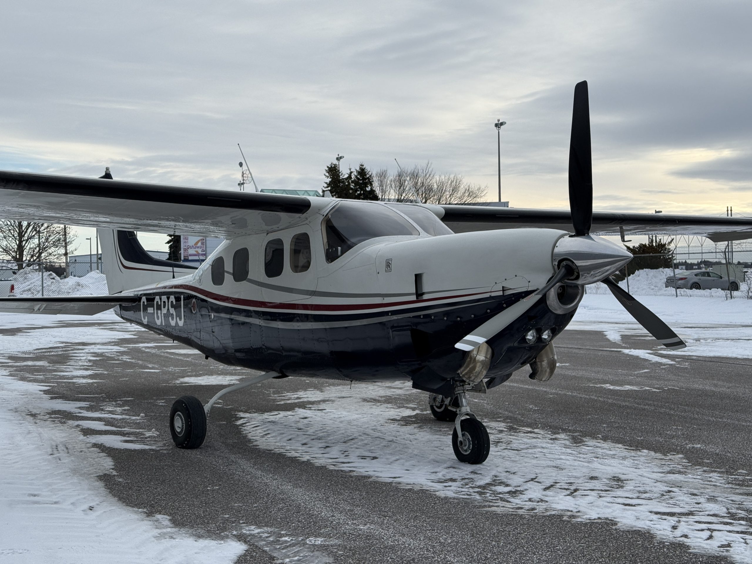 White twin engine propeller airplane parked on a snow covered tarmac