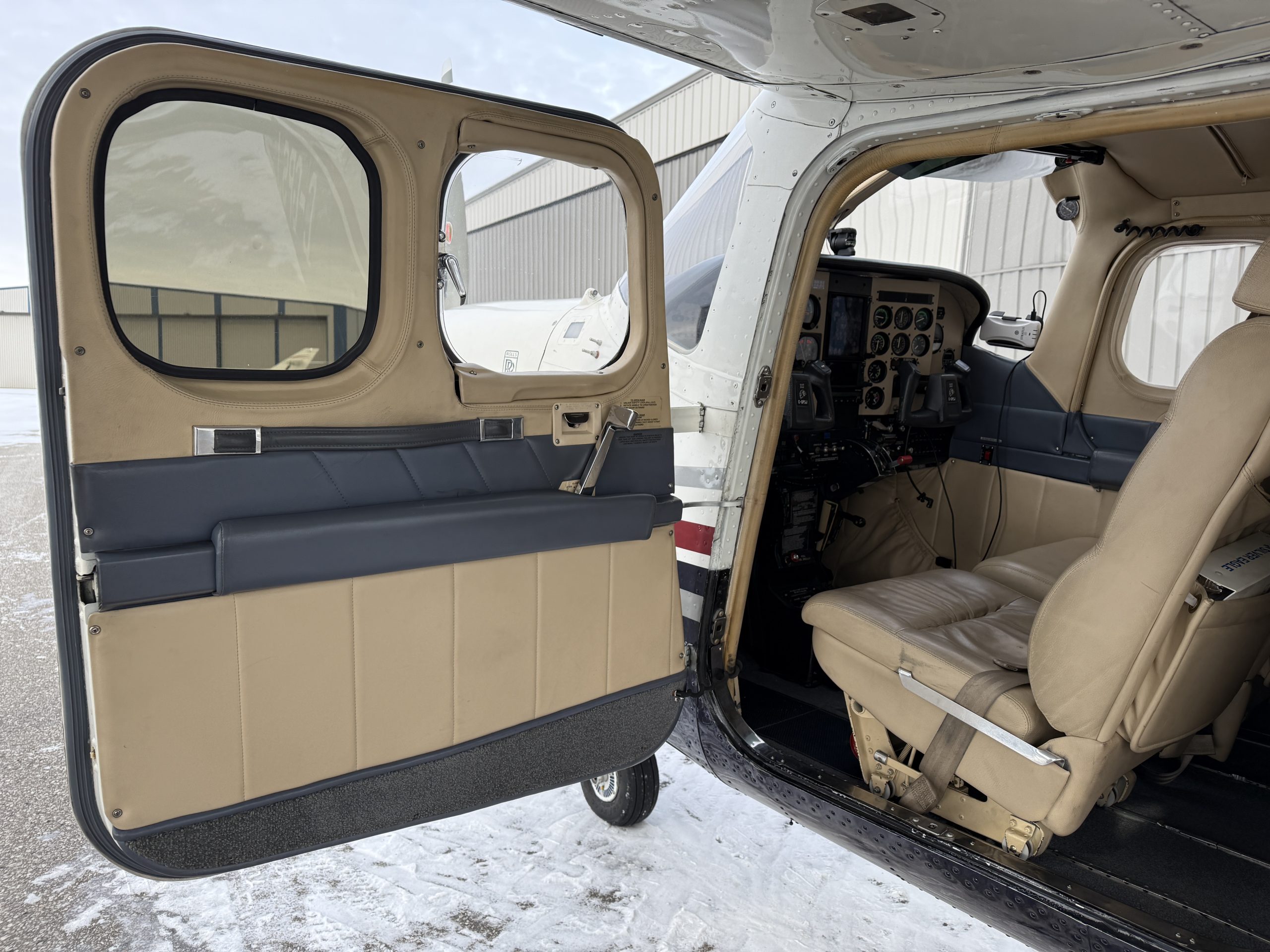 Open airplane door showing beige cabin interior and cockpit instruments visible through the doorway