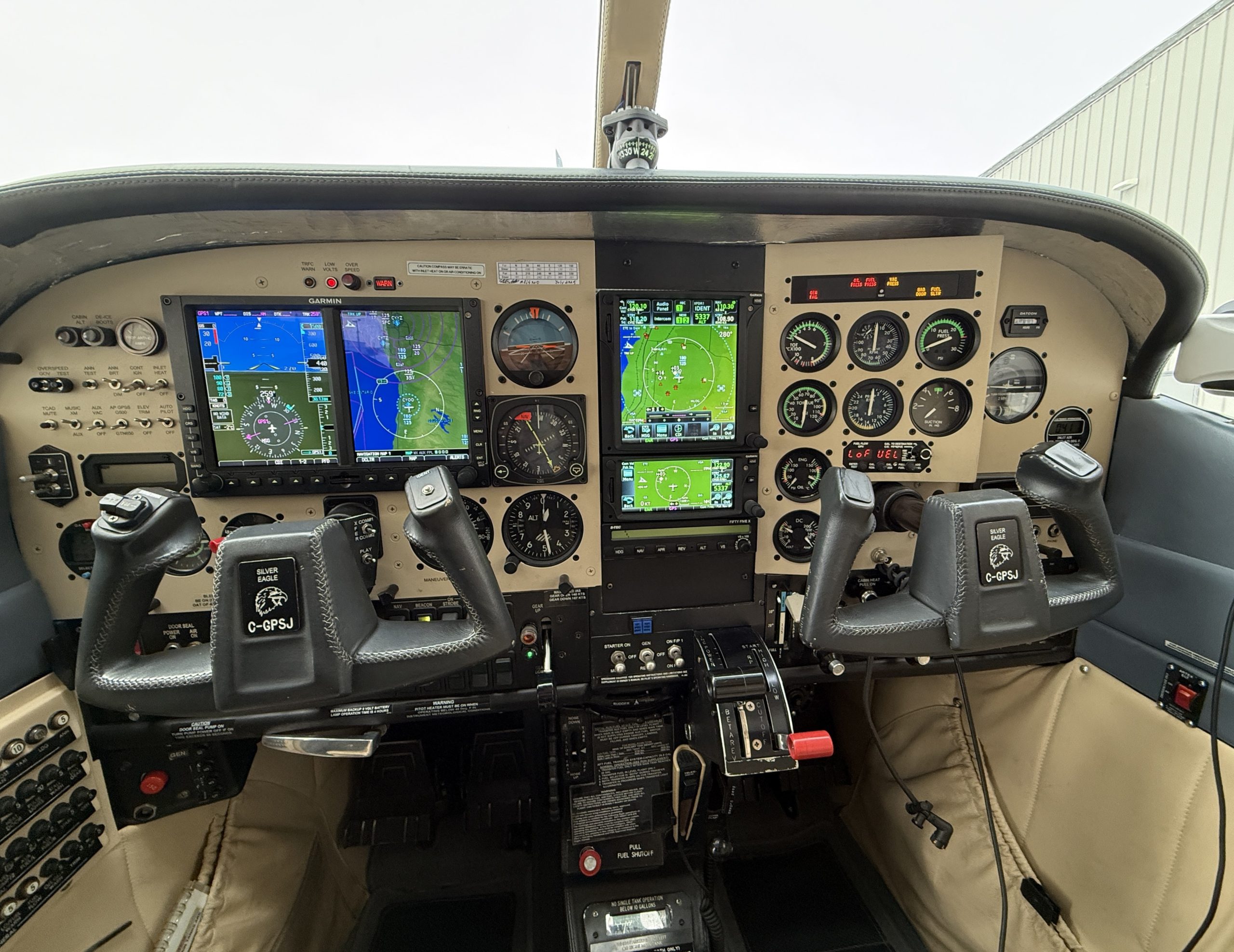 Small aircraft cockpit interior with Garmin avionics analog gauges and dual yokes on the center console