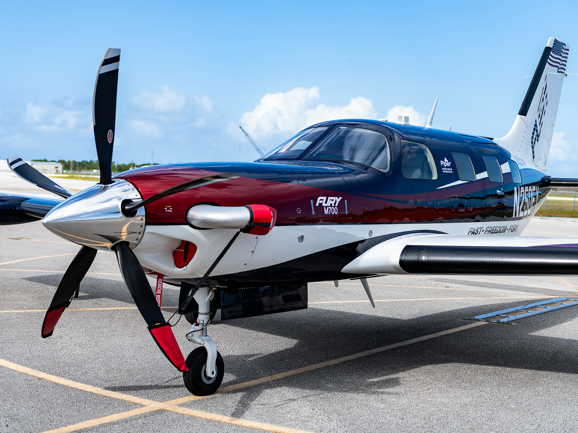 Side view of a blue and maroon turboprop airplane parked on an airport tarmac.