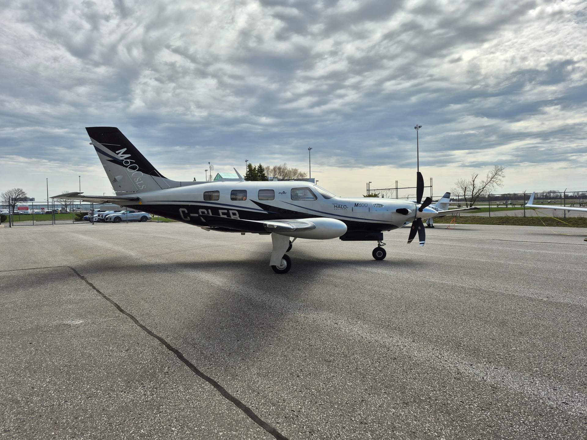 Piper M600 turboprop airplane parked on an airport apron with a cloudy sky above.