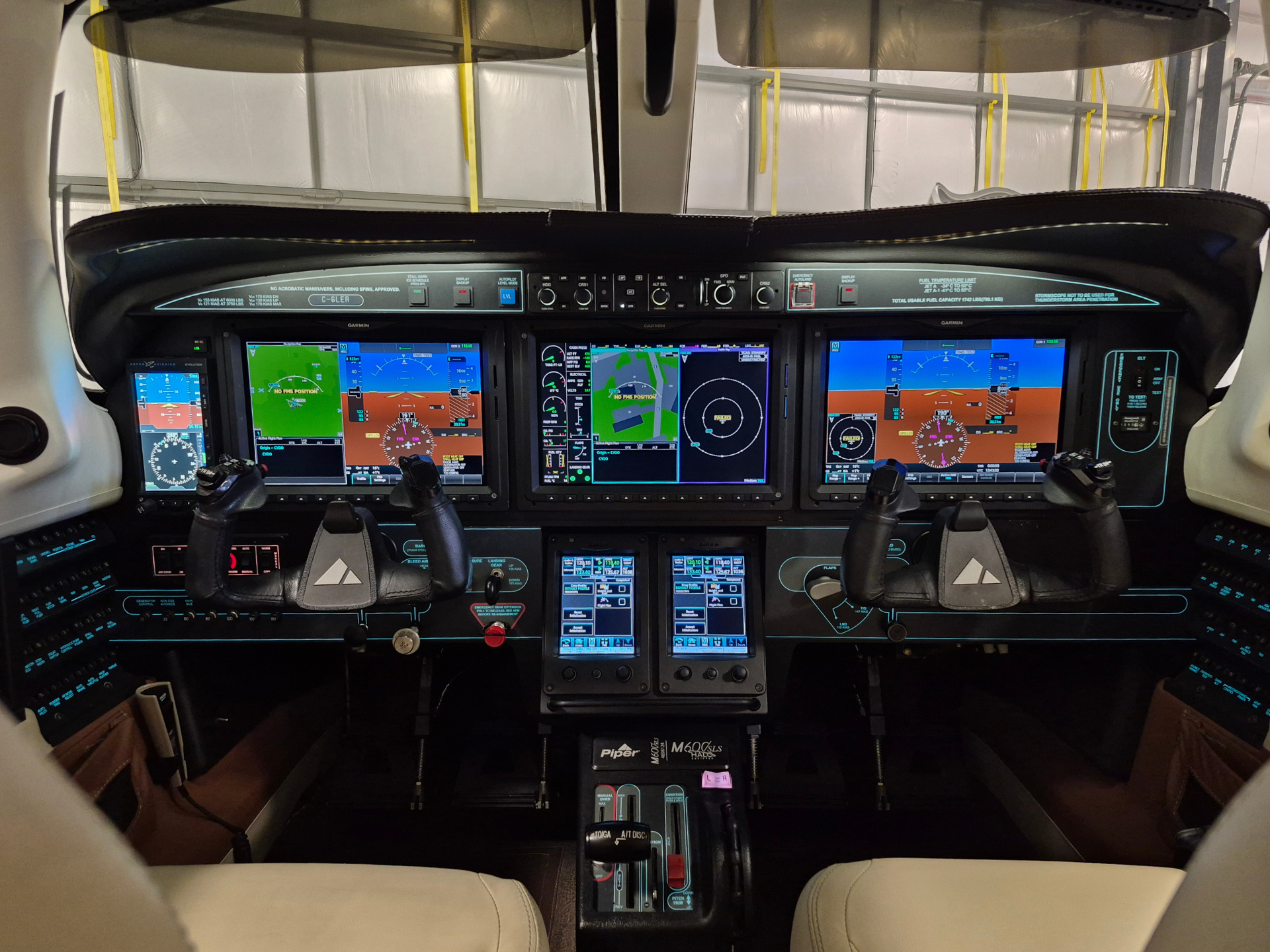 Glass-cockpit airplane interior with four main flight displays, dual yokes, and a central throttle console.
