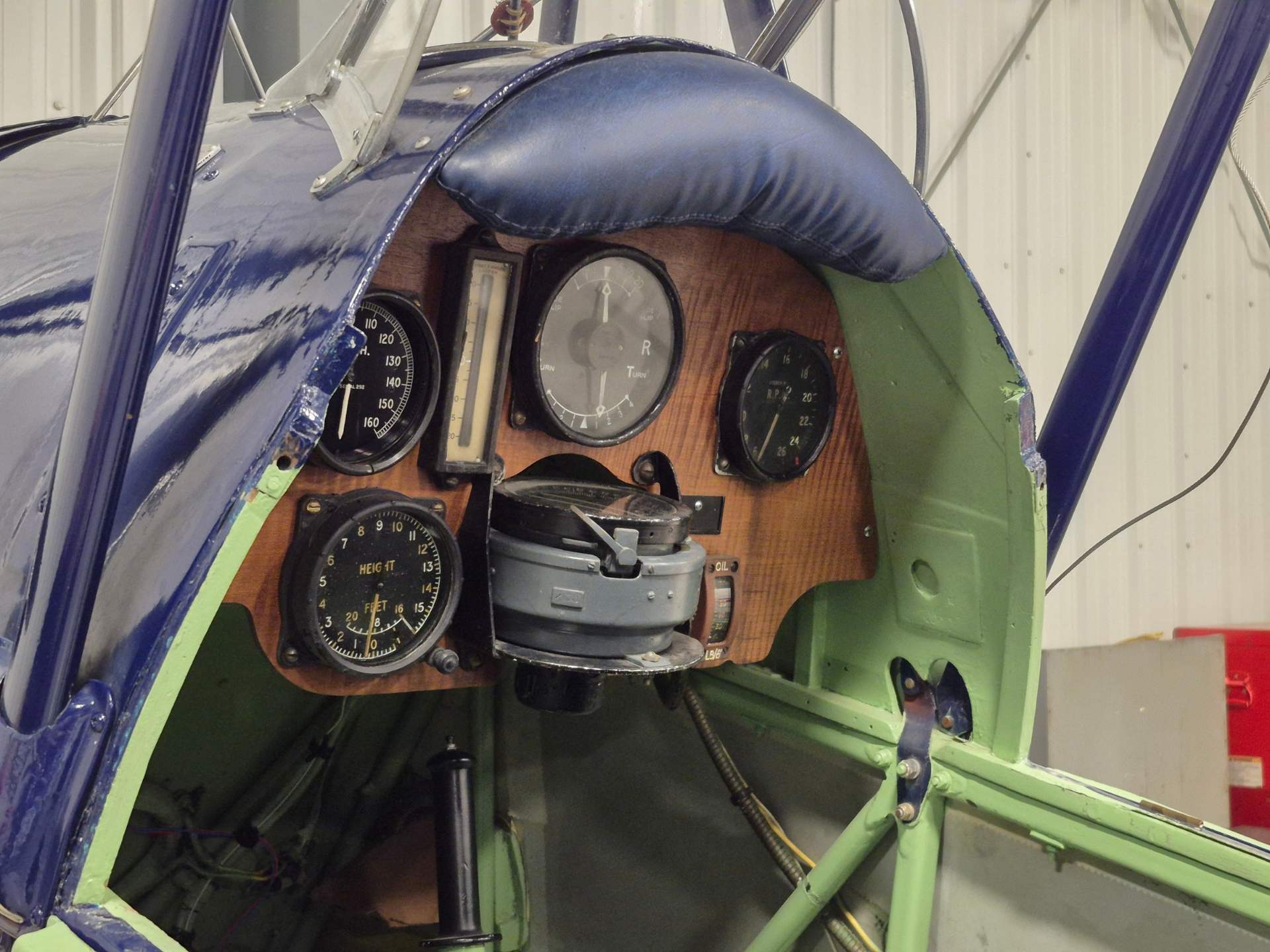 Close-up of a small aircraft cockpit with wooden panel and multiple analog gauges.