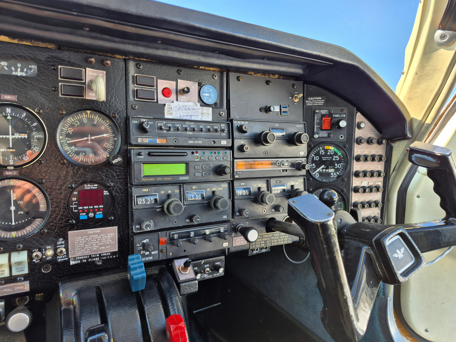 Full cockpit instrument panel with dials, switches, and radios inside a small airplane.