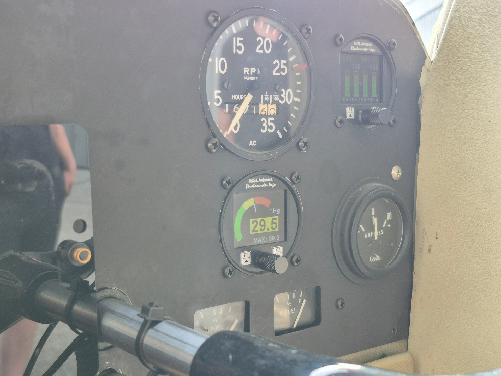 Close-up of an aircraft cockpit instrument panel showing a large round tachometer (RPM) and surrounding gauges, including fuel and amperage indicators.