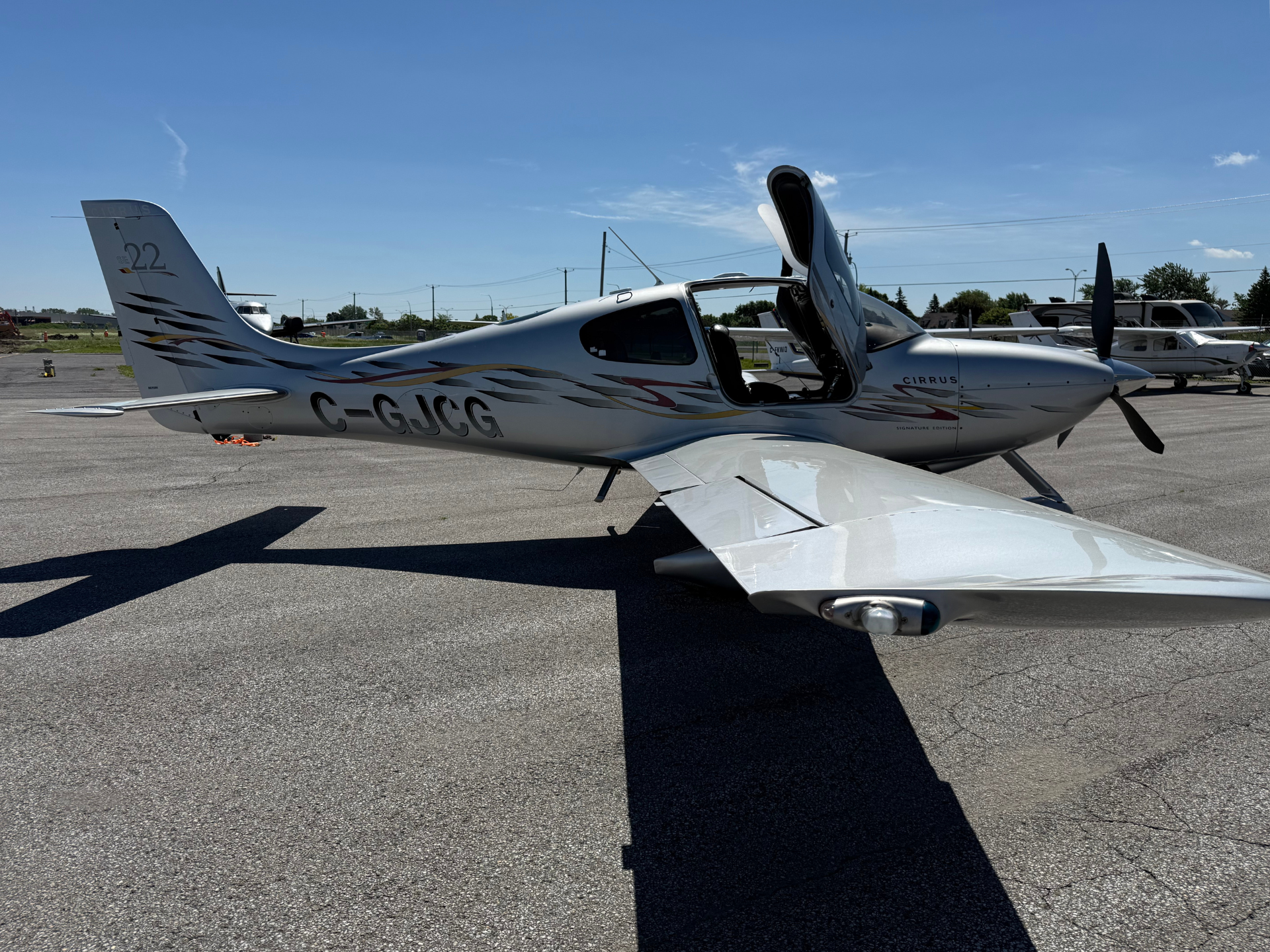 Private single-engine Cirrus airplane on the tarmac with its canopy open, under a clear blue skyр.