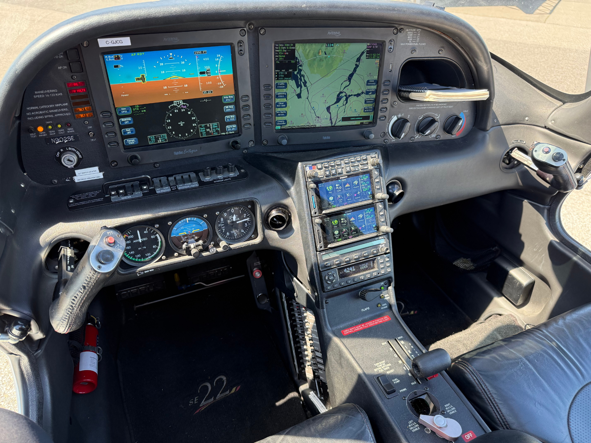 Cockpit of a small aircraft showing two large avionics screens, yoke, throttle quadrant, and a map display on the right screen.