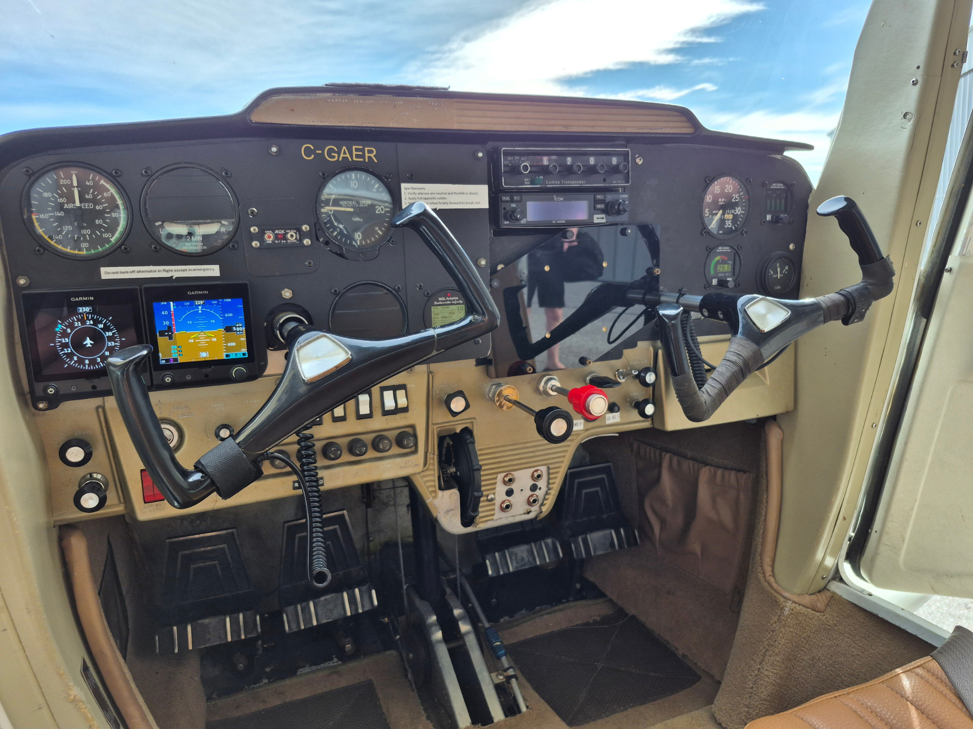 Interior view of a small airplane cockpit with dual yokes, analog gauges, and radio panel in use.