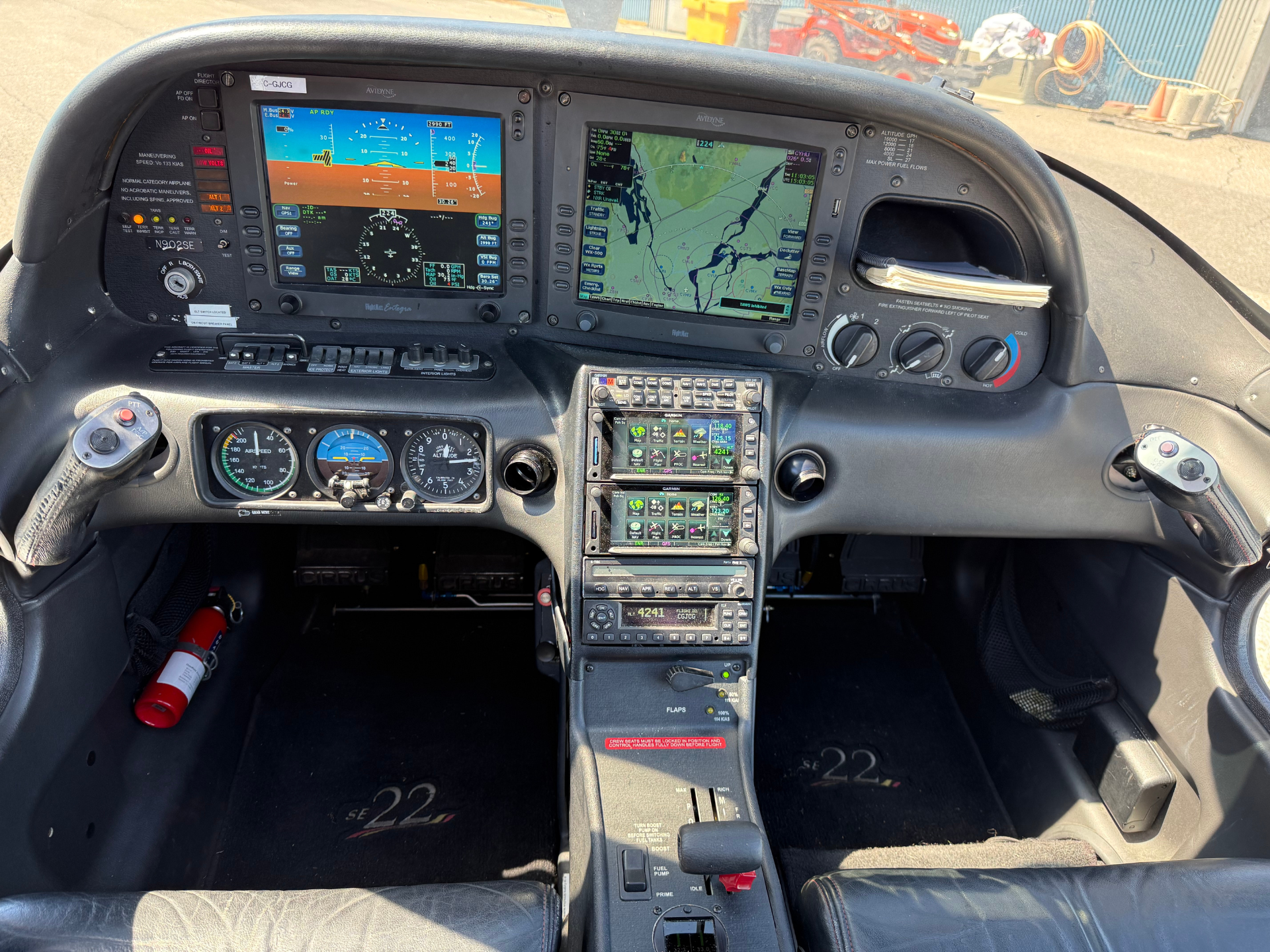 Pilot's cockpit with dual large flight displays and a central avionics stack, showing attitude and map screens in a small aircraft cabin.