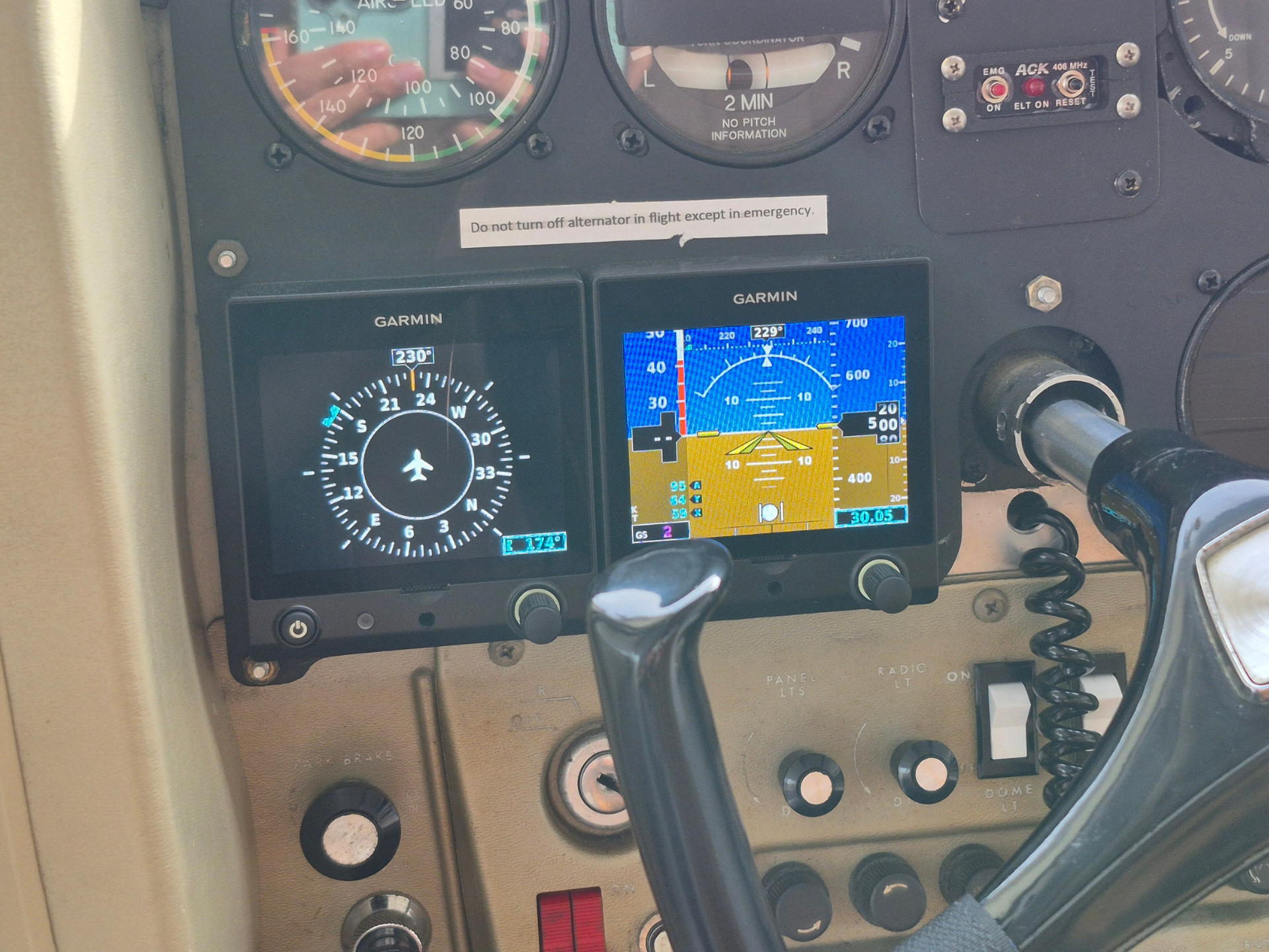 Pilot cockpit with two Garmin screens showing attitude and flight data, surrounding controls and yoke visible.