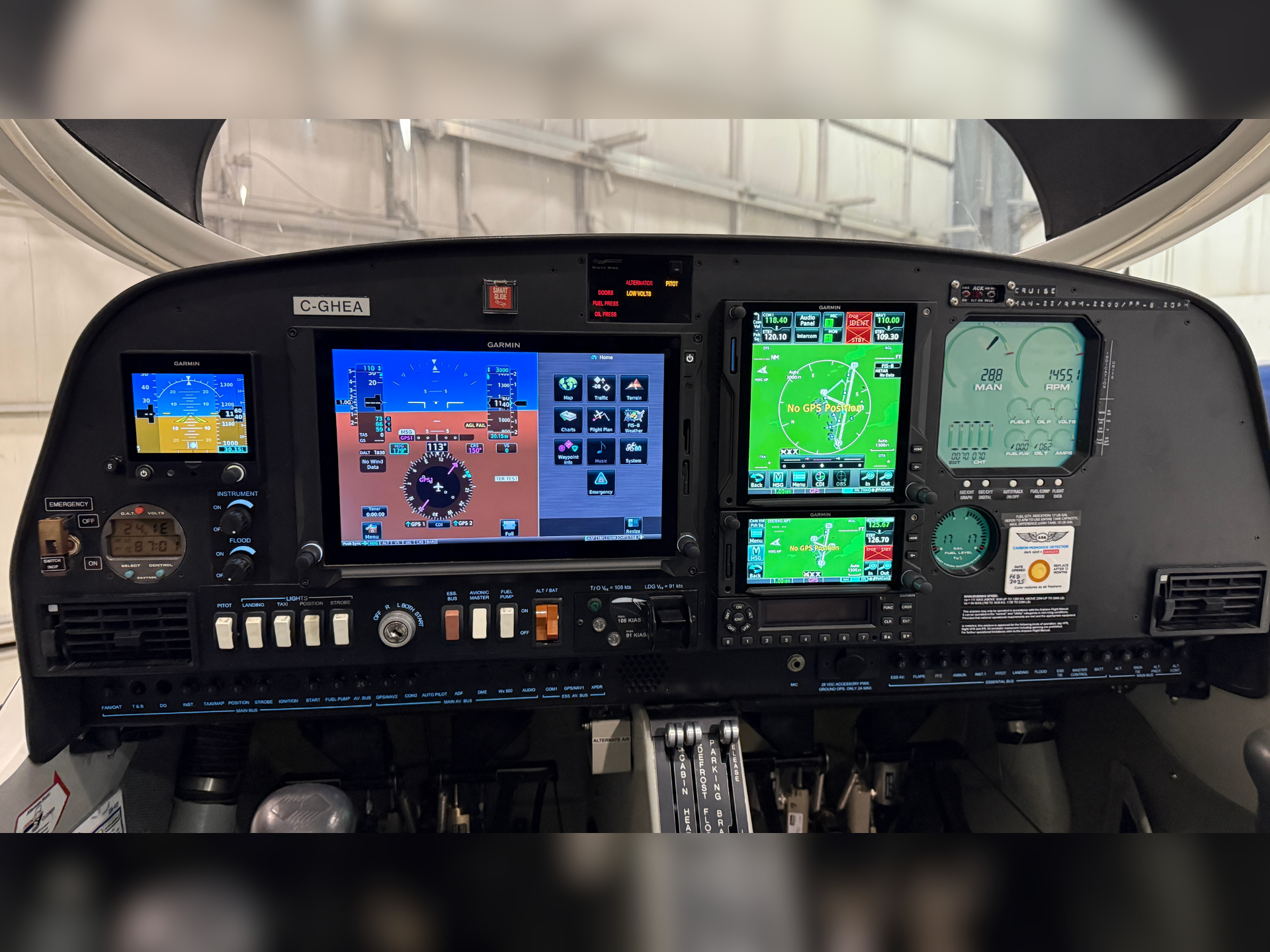 Cockpit instrument panel with multiple Garmin glass screens and controls in a small airplane cabin.