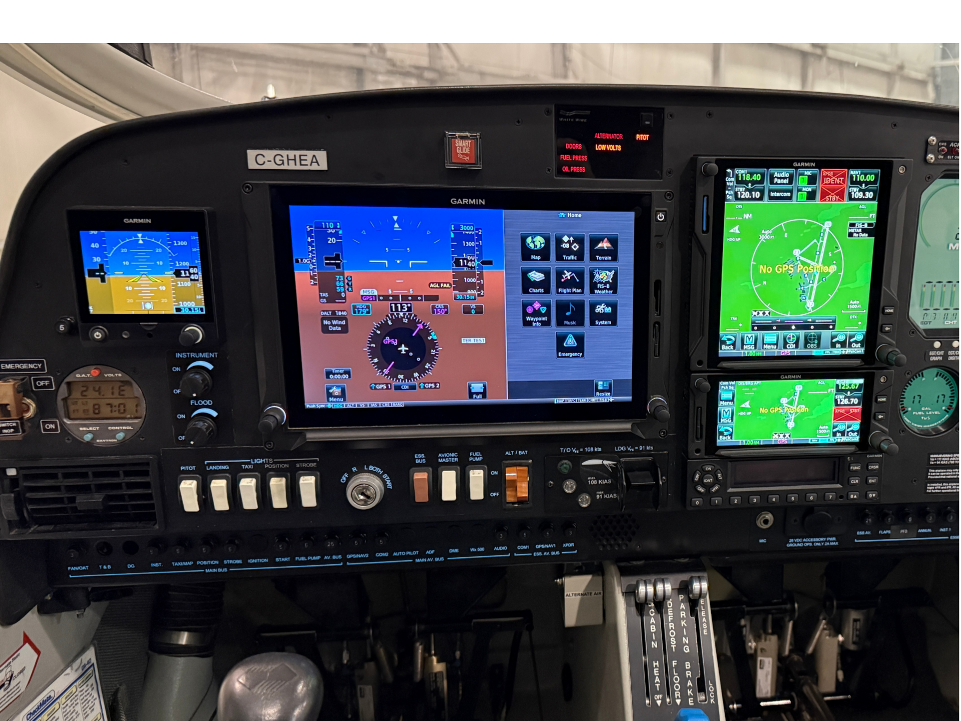 Aircraft cockpit instrument panel with Garmin displays and control switches visible.