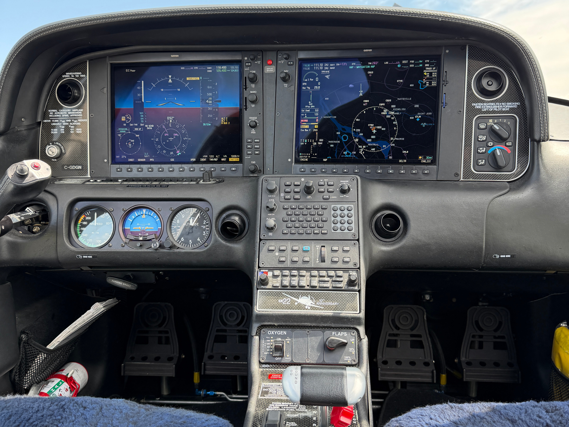 Cockpit with two Garmin displays showing flight data (left) and navigation map (right), plus center keypad and throttle.