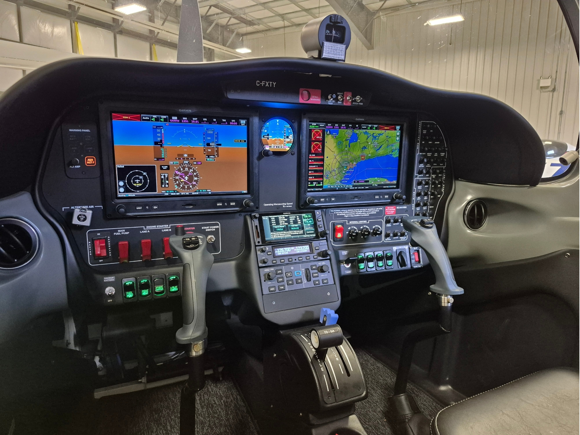 Cockpit of a small airplane with two large Garmin displays, navigation map, and flight instruments visible between the yokes.