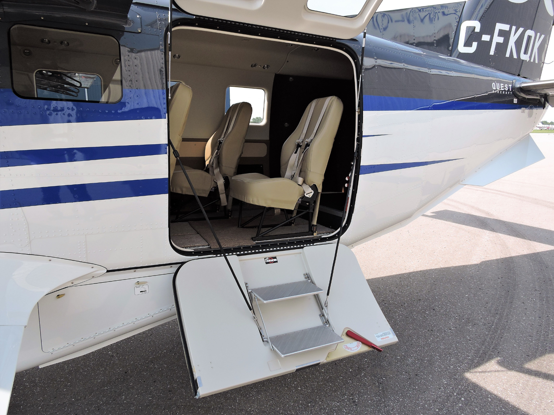 Open side door of a white and blue helicopter showing beige passenger seats and retractable stairs