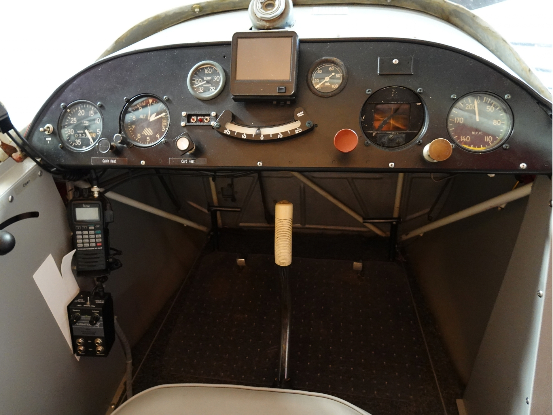 Small airplane cockpit dashboard with round gauges a central square screen and a throttle lever in the foreground