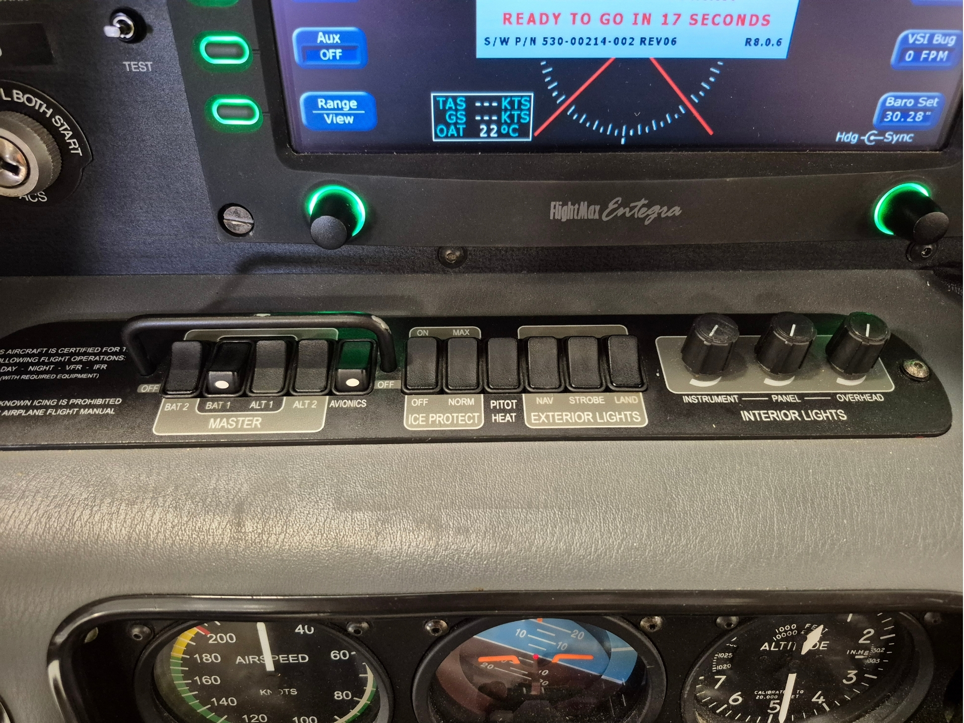 Close up of a small aircraft cockpit green backlit knobs a digital flight display and exterior light control labels on the panel below