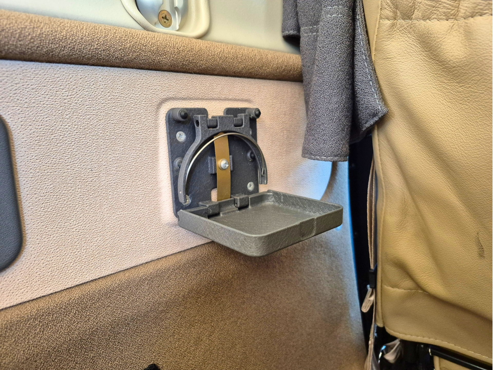 Open car ashtray mounted to a beige interior panel of a vehicle