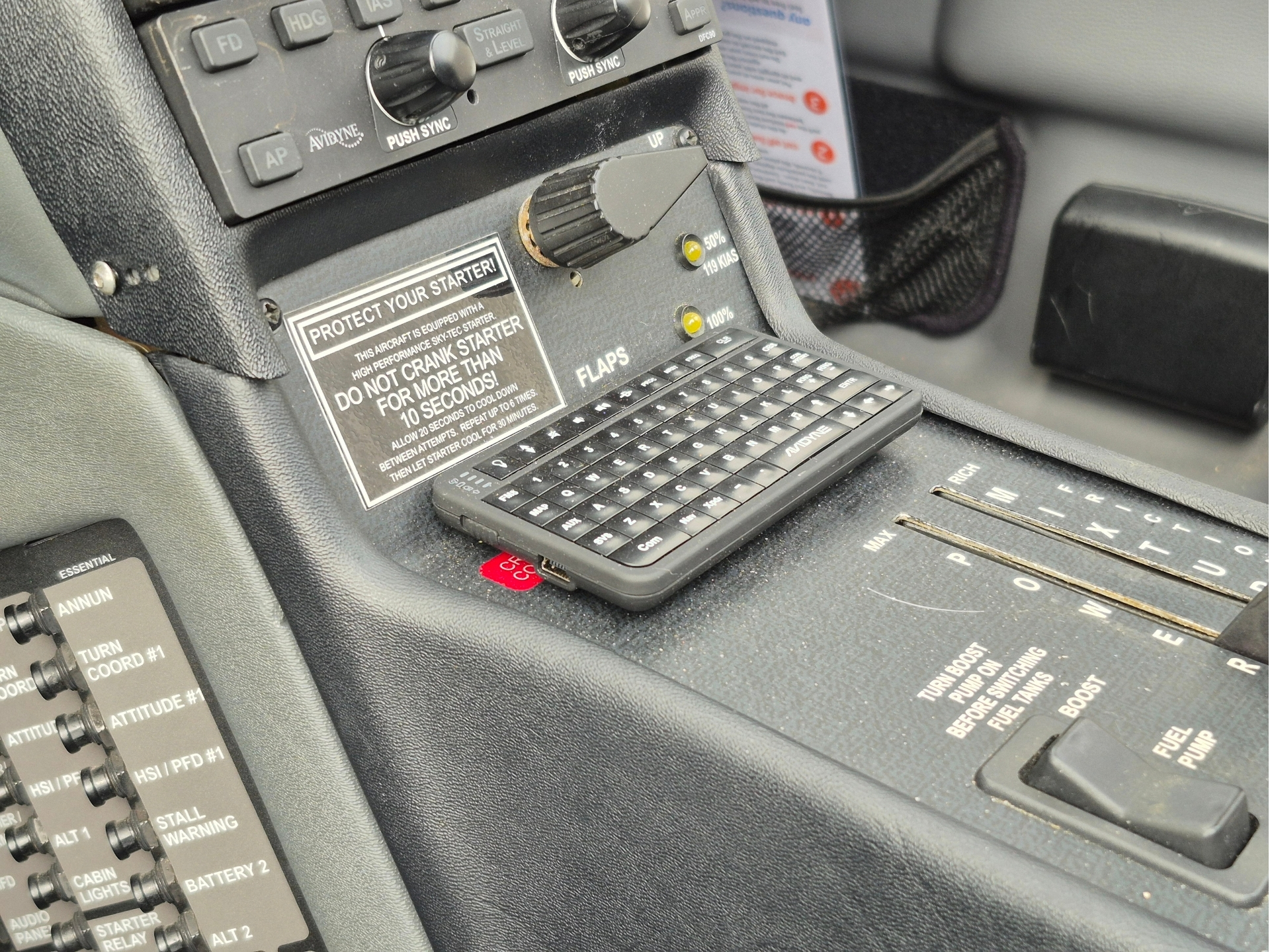 Cockpit center console with a small onboard keyboard and a warning plaque reading PROTECT YOUR STARTER Do not crank starter