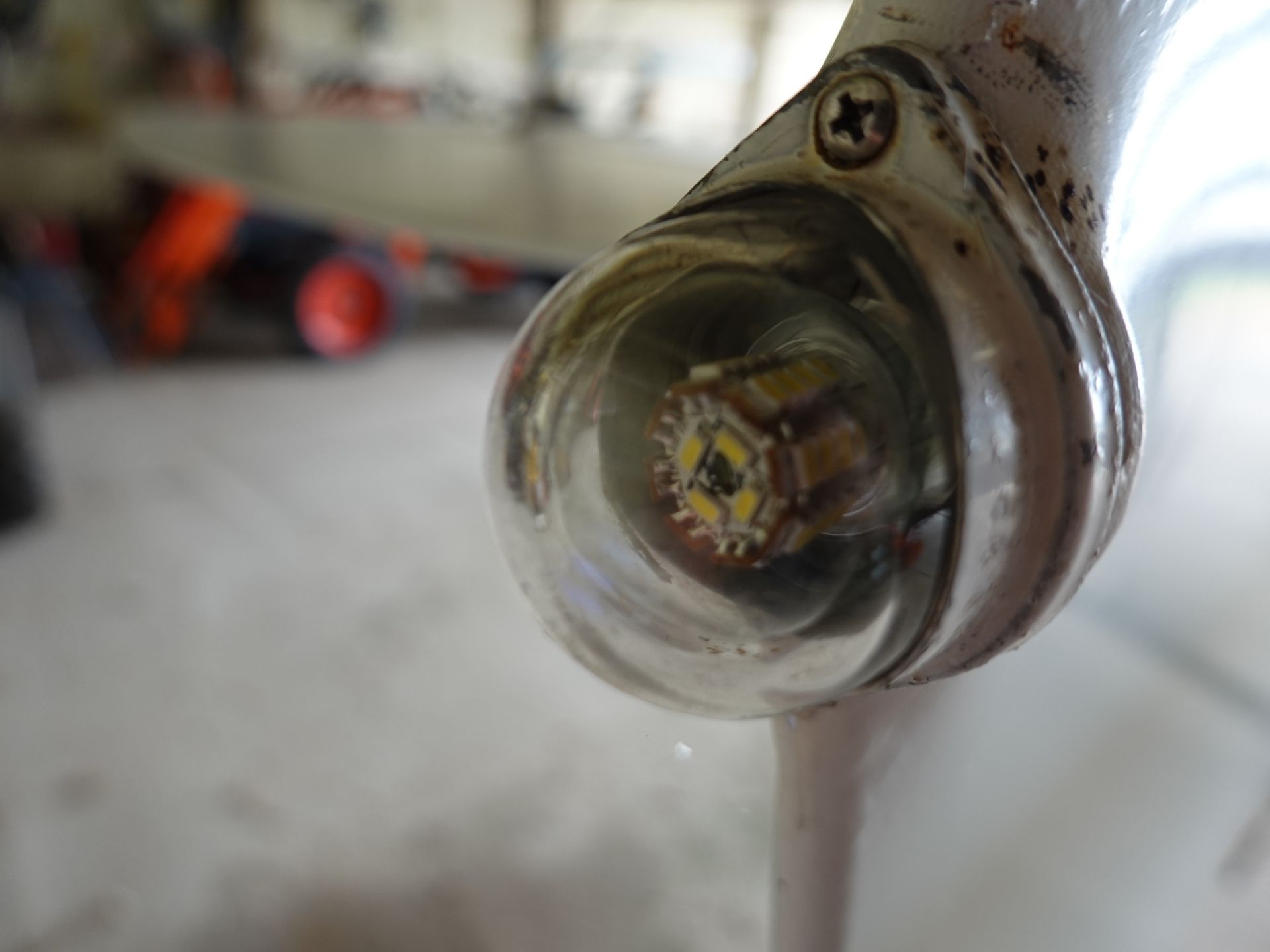 Close-up of a shiny, chrome knob with rust, set against a blurred workshop background.
