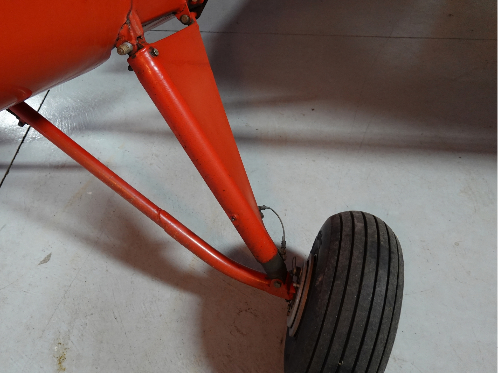 Close up of a red aircraft landing gear leg and wheel on a concrete floor