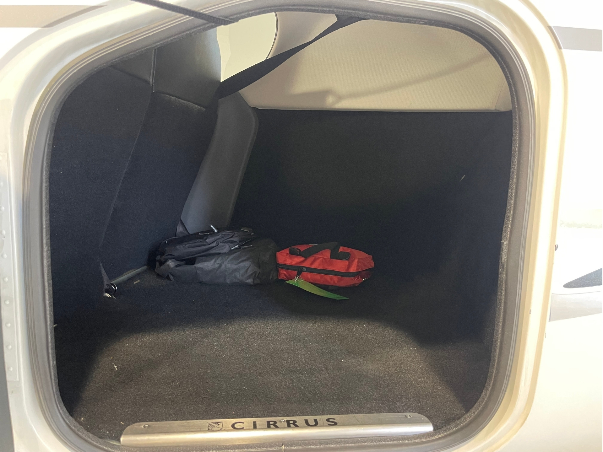 Open car trunk showing two bags black and red on the dark carpeted floor of the cargo area