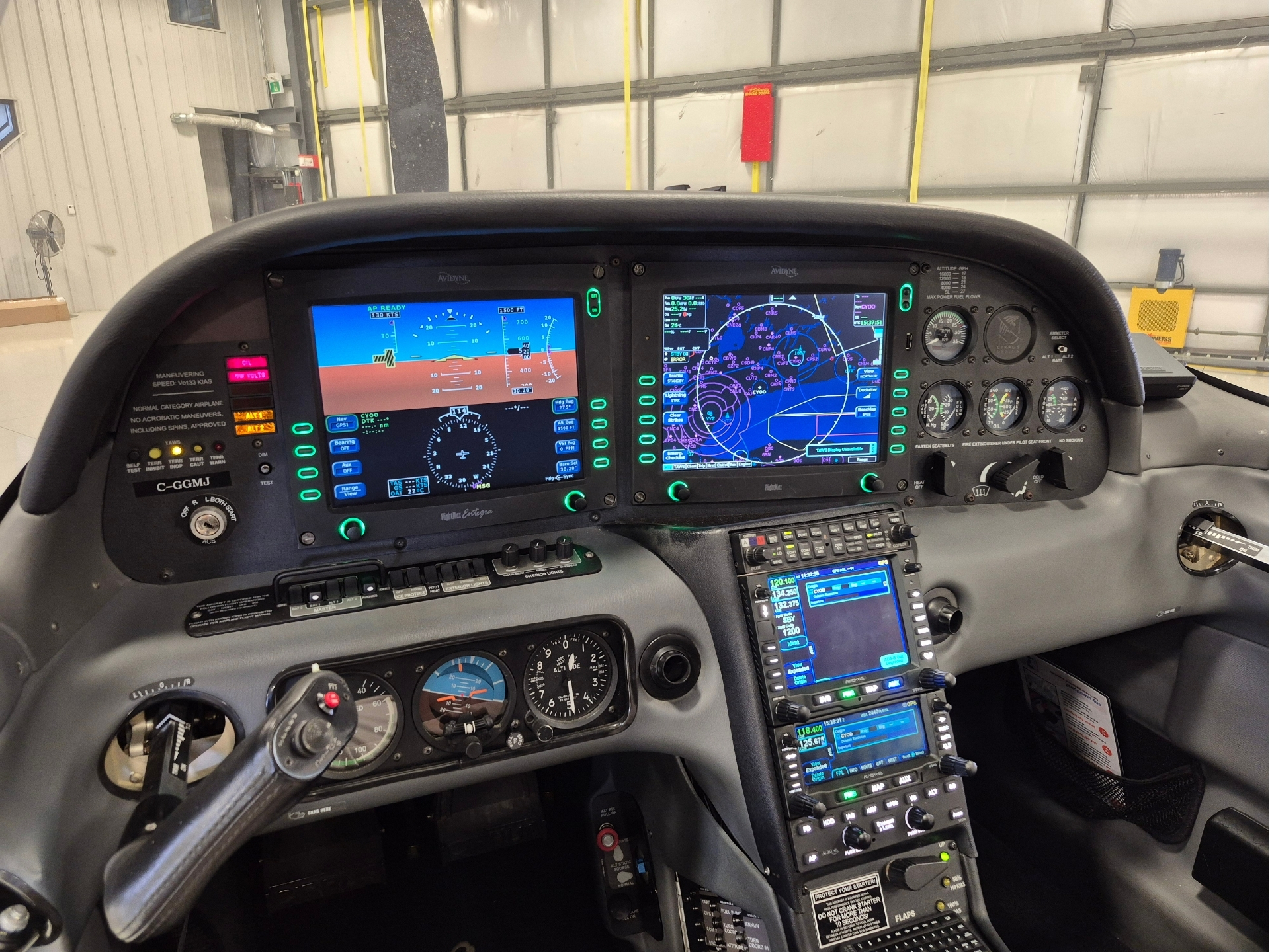 Cockpit of a small aircraft with two large glass cockpit displays digital instruments and a central control console inside a hangar