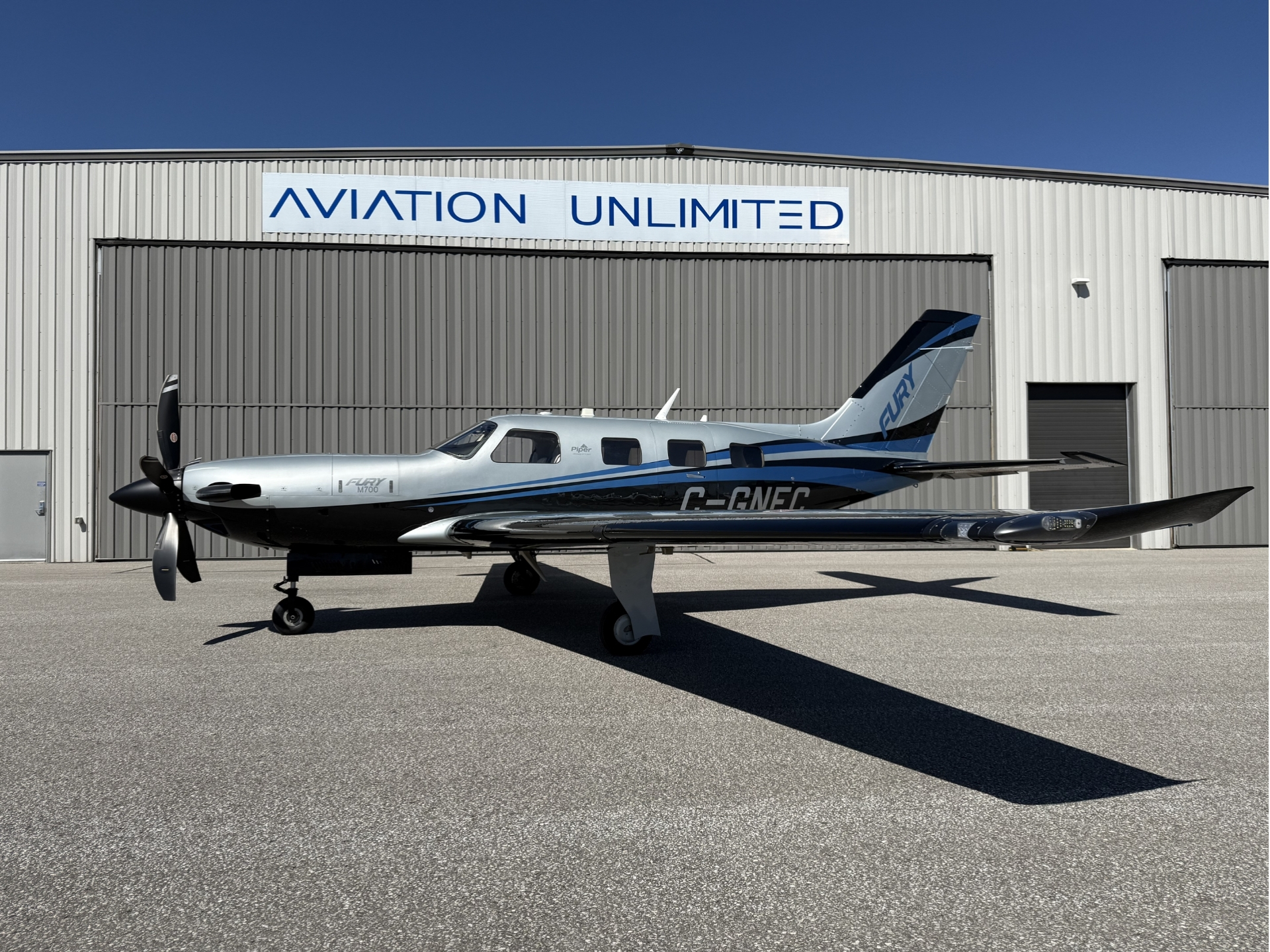 Piper M700 private singleengine turboprop parked on the tarmac in front of an Aviation Unlimited hangar sign