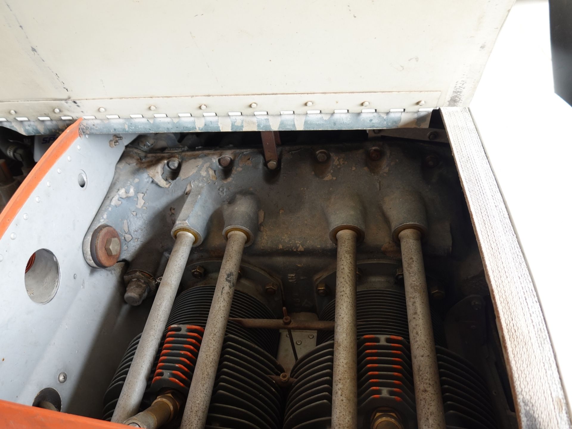 Close-up of an industrial engine bay with rusted pipes, a riveted metal panel, and ribbed components in the lower section.