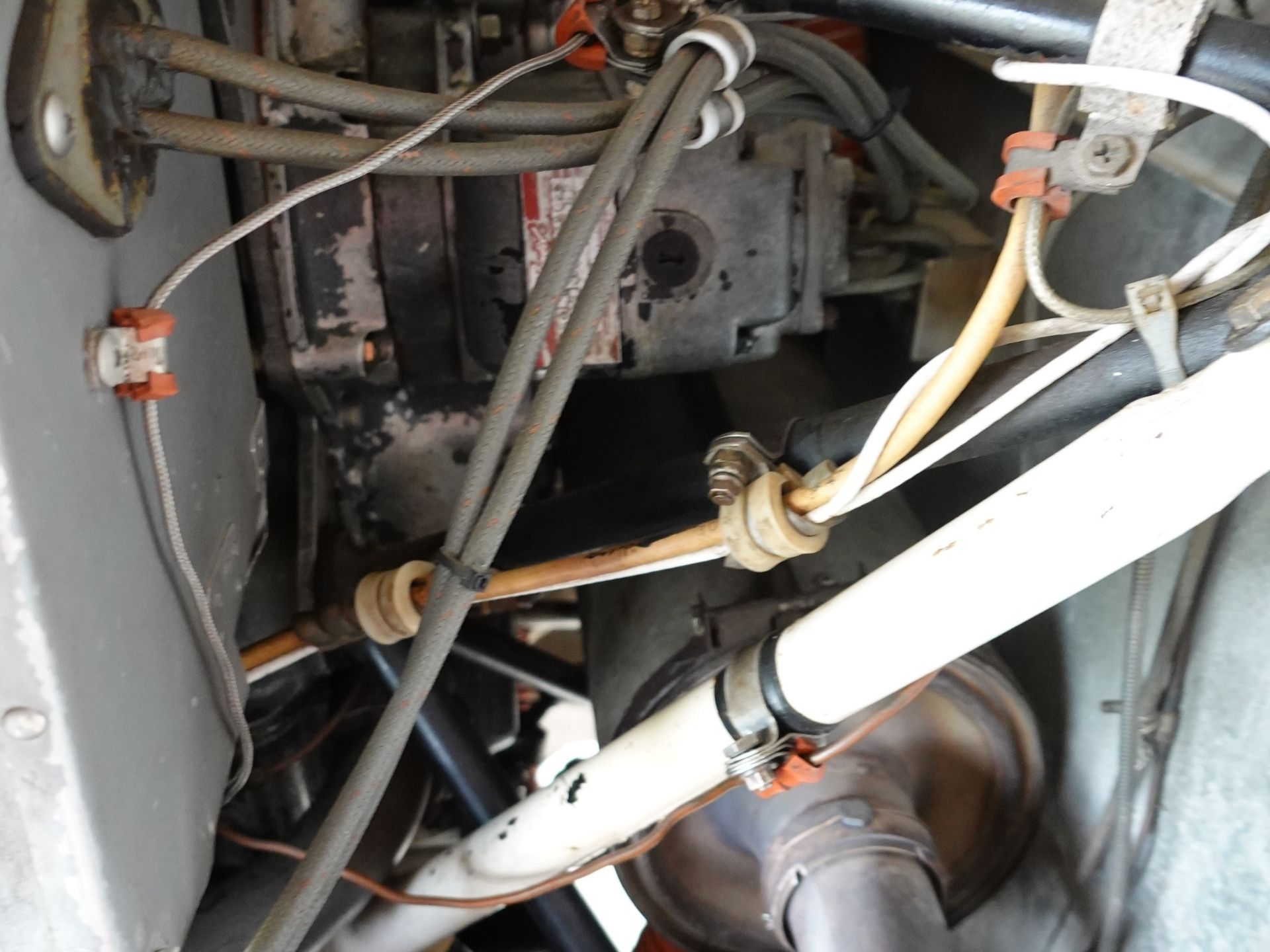 Close-up of a dusty motor with tangled wires and hoses inside a metal enclosure.