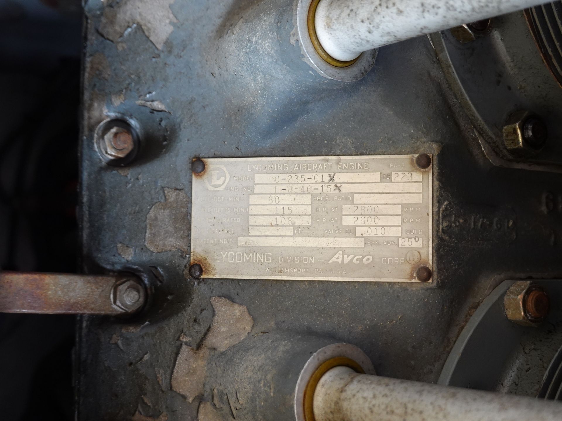 Metal nameplate on a dusty engine housing reading Lycoming Aircraft Engine with model and serial information visible but partly worn by corrosion.