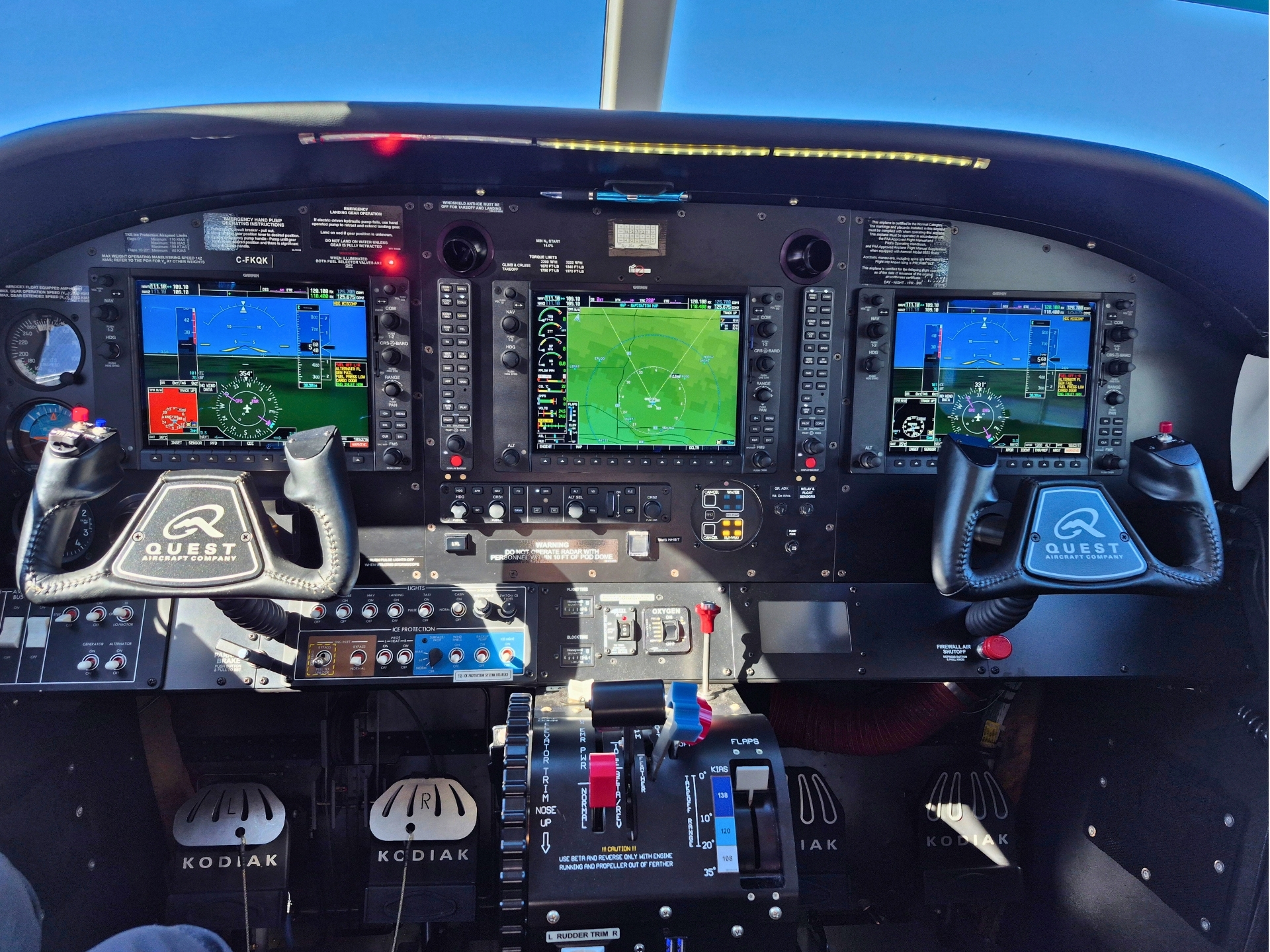Flight deck of a Quest Kodiak aircraft with three glass cockpit displays and dual yokes
