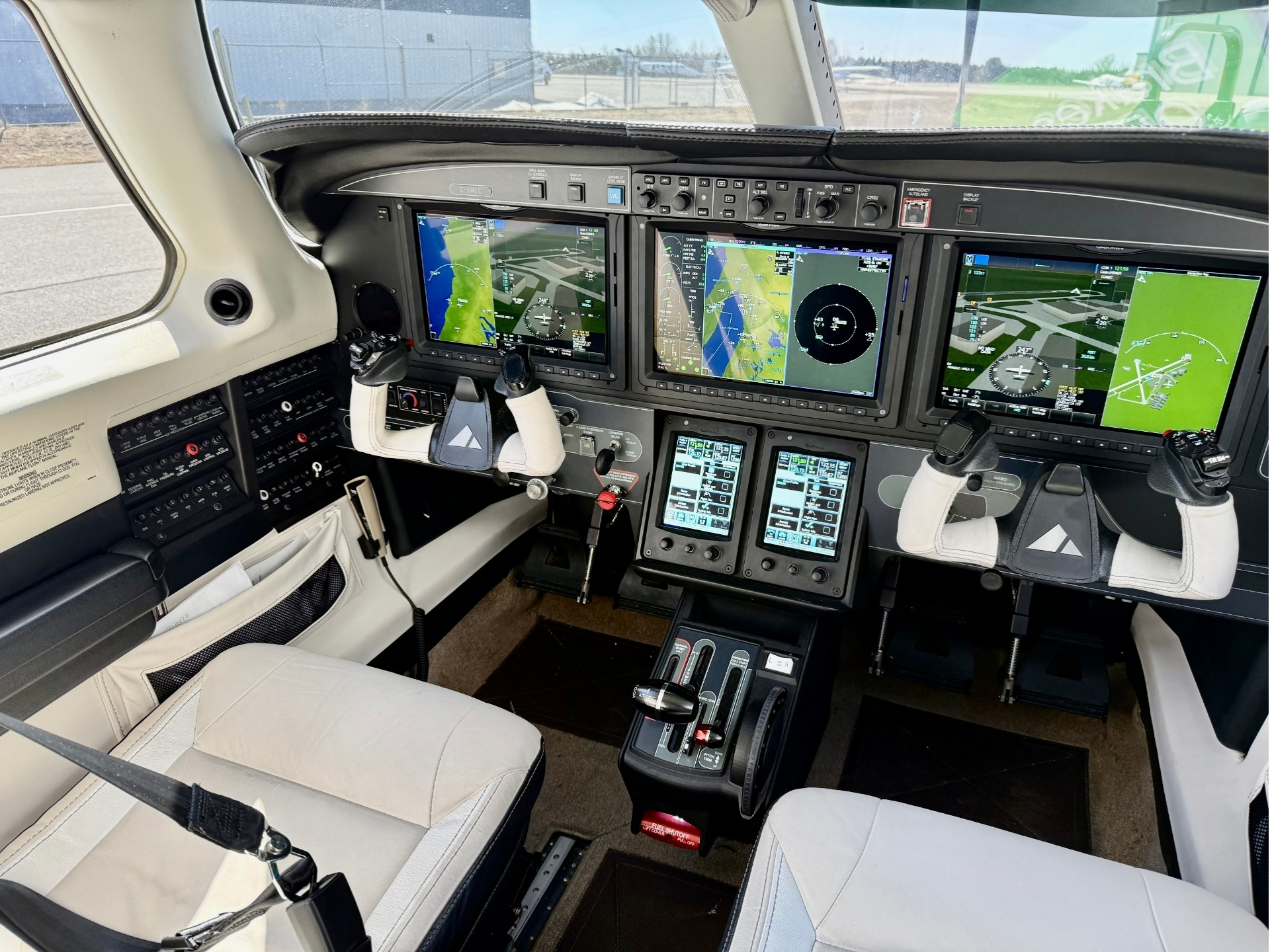 Cockpit of a small aircraft with multiple touchscreen flight displays dual yoke controls and center console panels